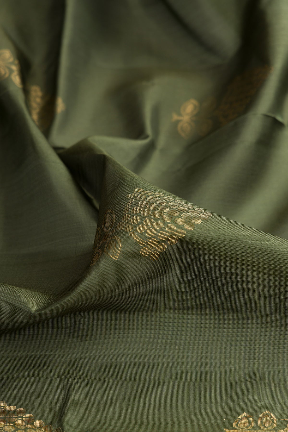 Close up of Pure Silk Mehandi Green Soft Saree with Zari Butta on the body and Zari Border.  displaying folds