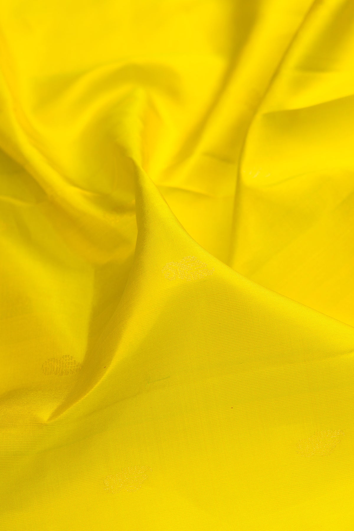 Close up of Pure Silk Lemon Yellow Soft Saree with Zari Butta on the body and Zari Border.  displaying folds