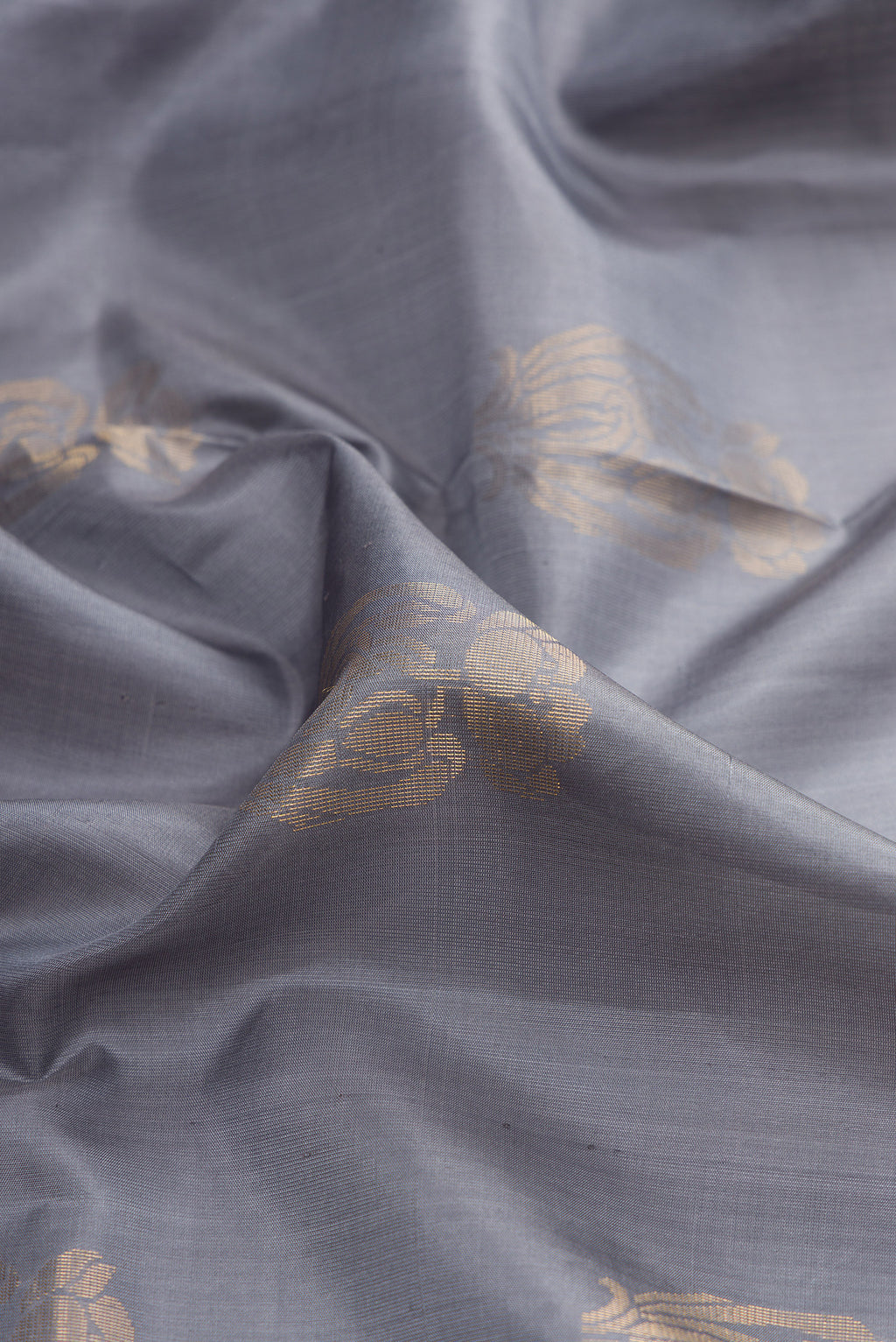 Close up of Pure Silk Grey Soft Saree with Zari Butta on the body and Zari Border.  displaying folds