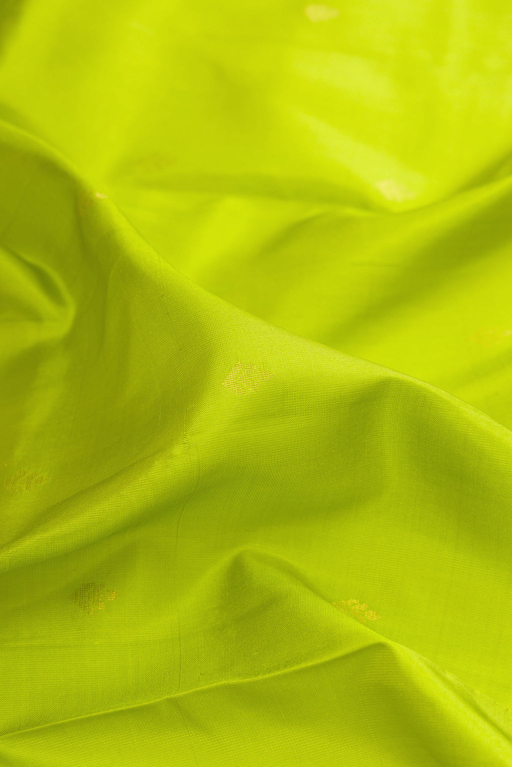 Close up of Pure Silk Parrot Green Soft Saree with Zari Butta on the body and Zari Border.  displaying folds