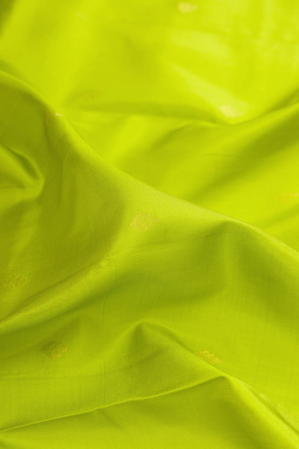 Close up of Pure Silk Parrot Green Soft Saree with Zari Butta on the body and Zari Border.  displaying folds