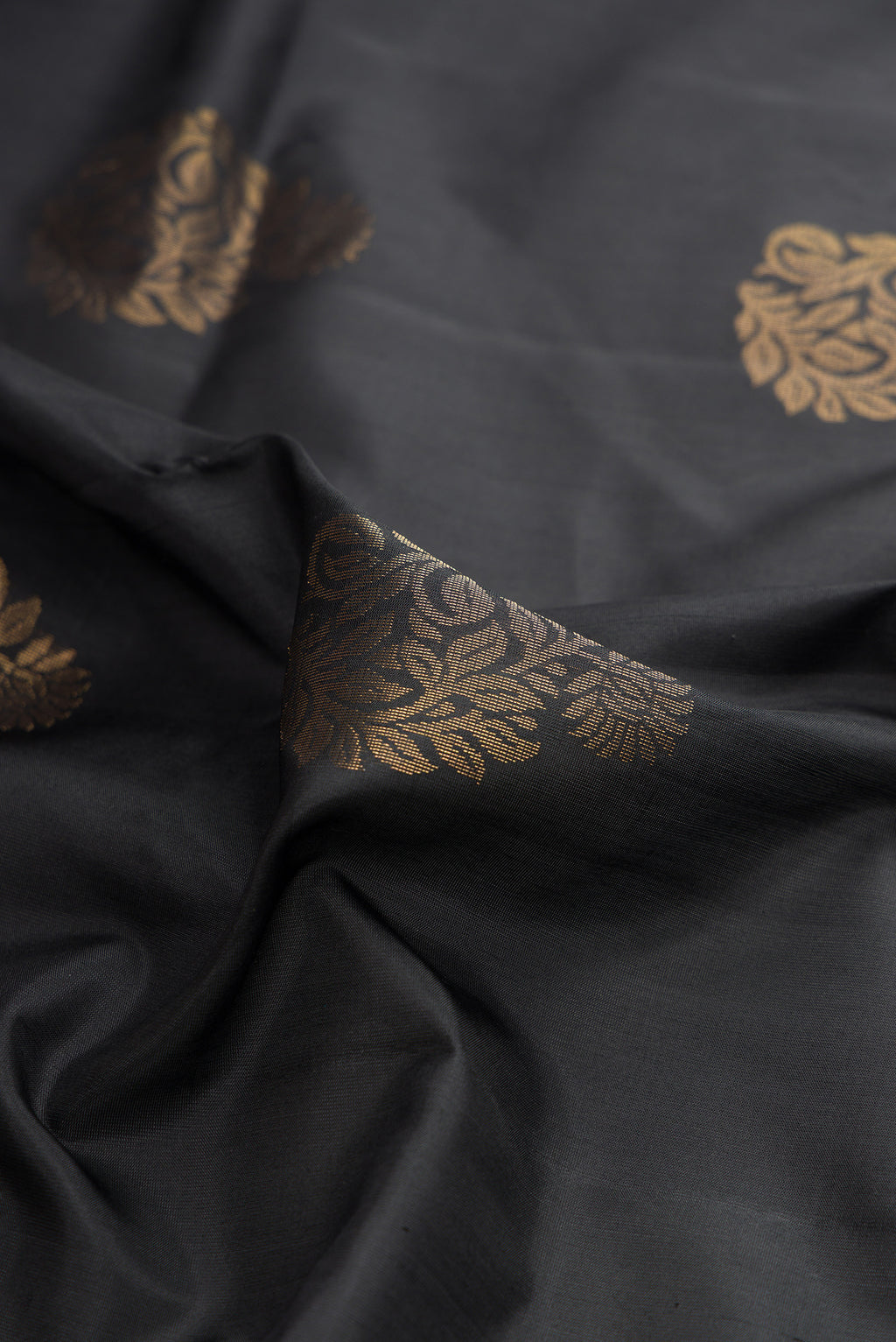Close up of Pure Silk Black Soft Saree with Zari Butta on the body and Zari Border.  displaying folds