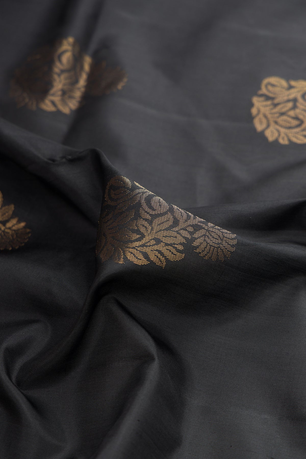 Close up of Pure Silk Black Soft Saree with Zari Butta on the body and Zari Border.  displaying folds