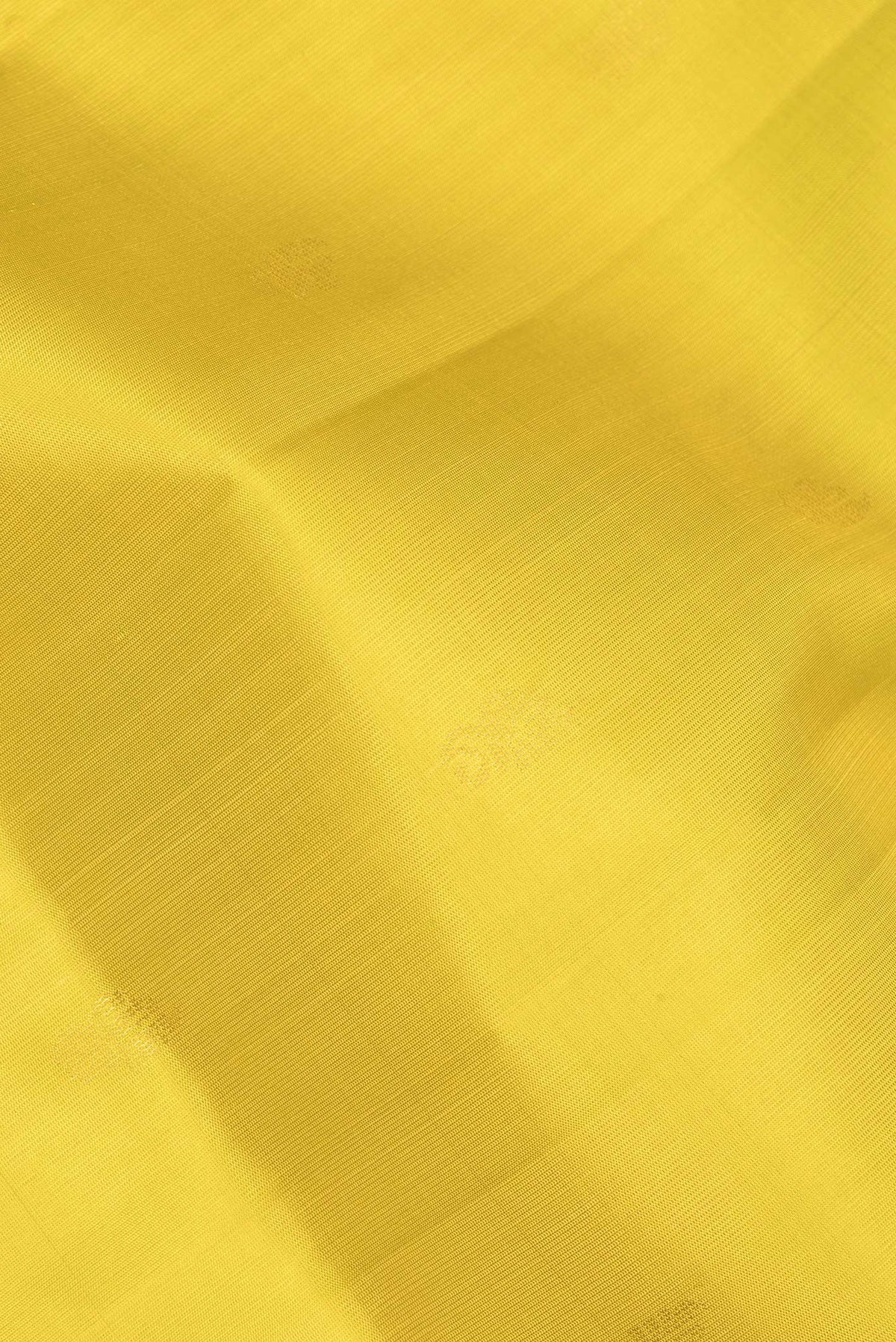 Close up of Pure Silk Lemon Yellow Soft Saree with Zari Butta on the body and Zari Border.  displaying folds