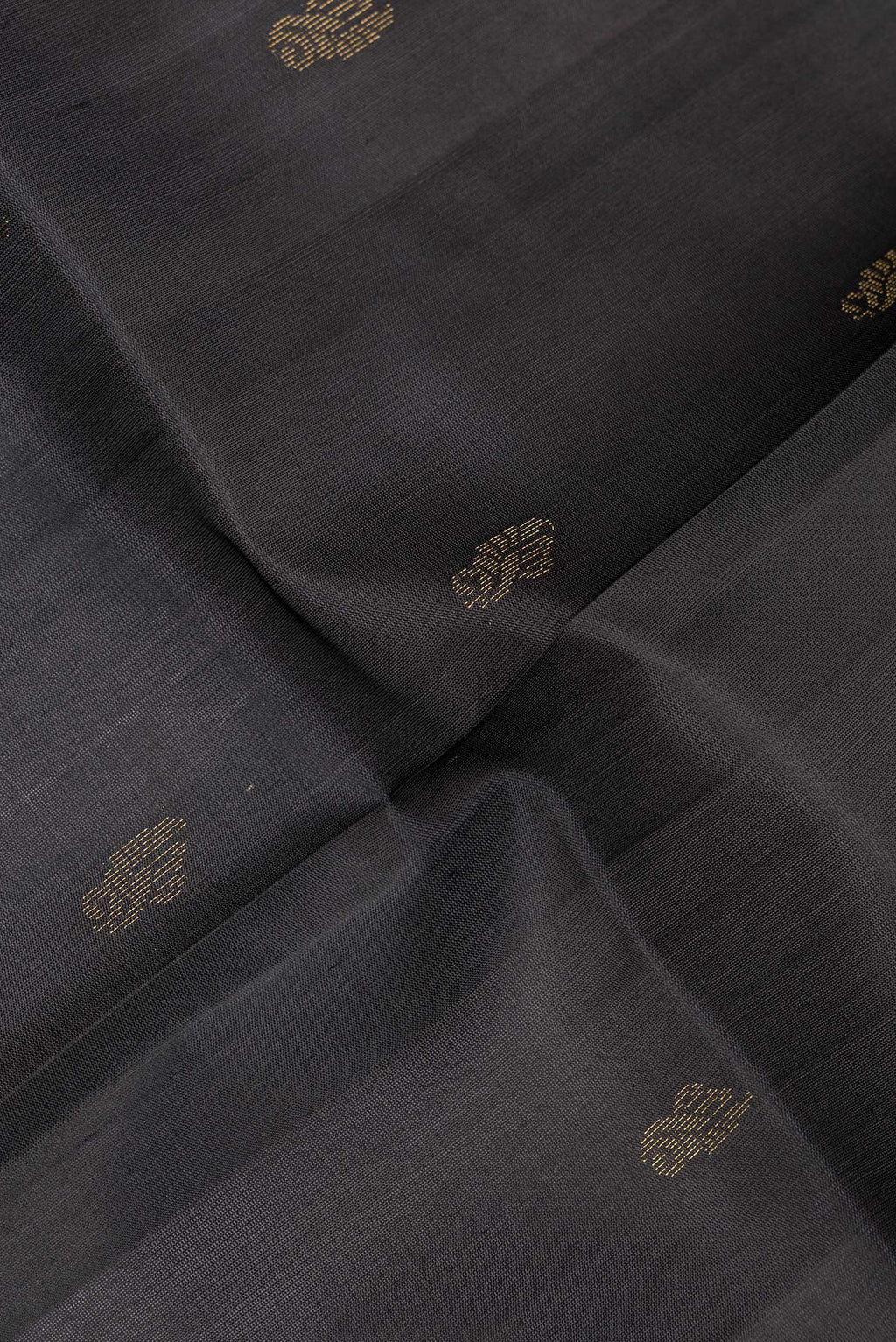 Close up of Pure Silk Black Soft Saree with Zari Butta on the body and Zari Border.  displaying folds
