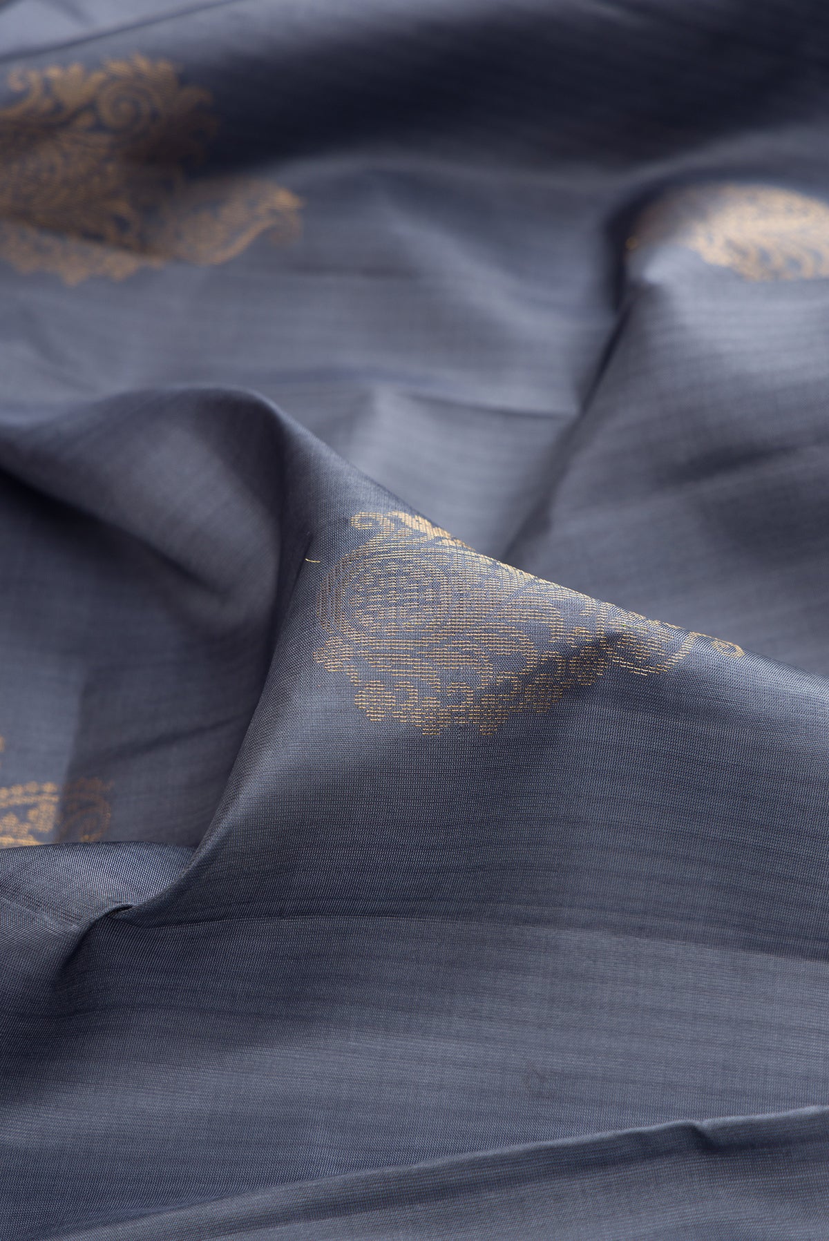Close up of Pure Silk Grey Soft Saree with Zari Butta on the body and Zari Border.  displaying folds