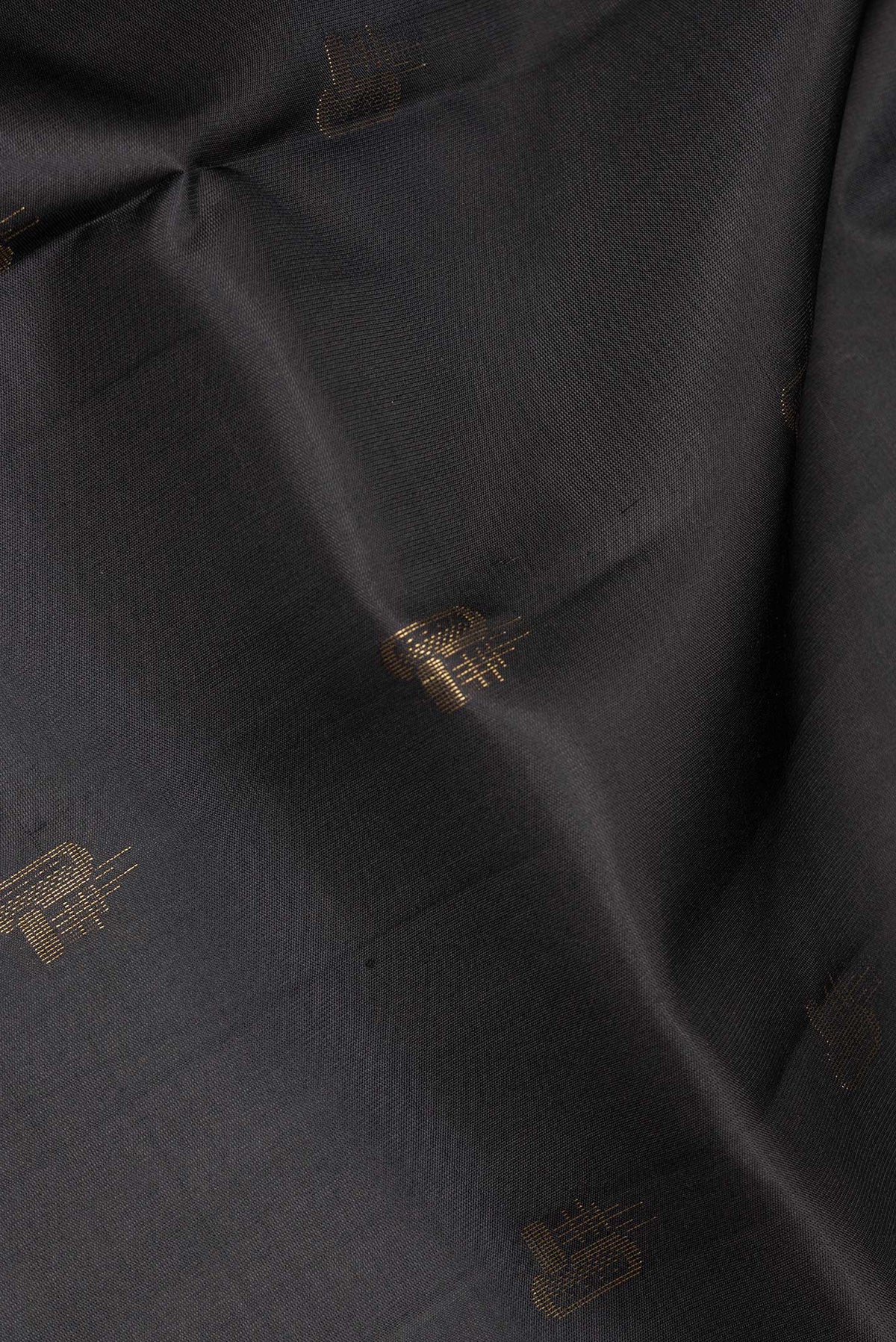 Close up of Pure Silk Black Soft Saree with Zari Butta on the body and Zari Border.  displaying folds