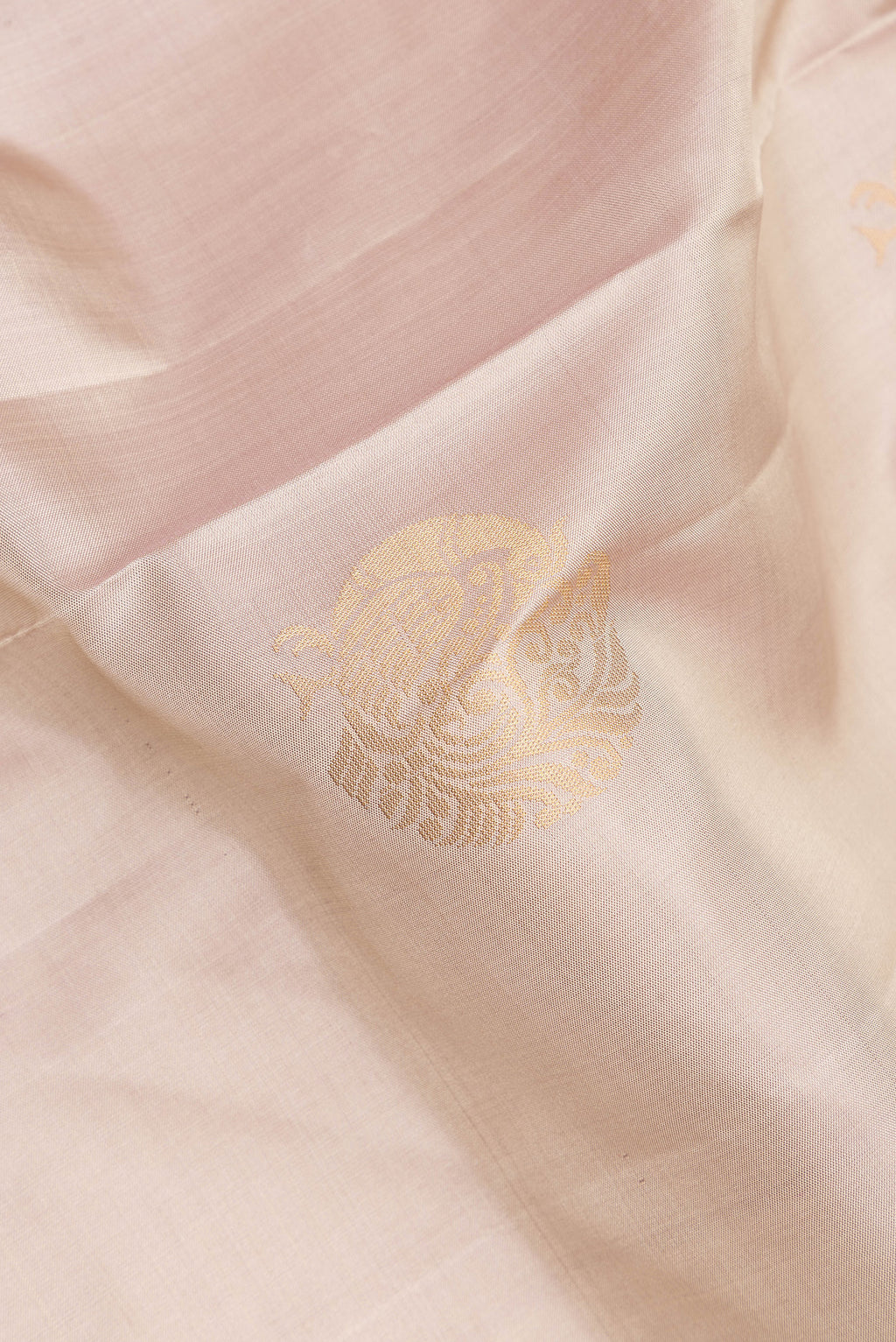 Close up of Pure Silk Rose Gold Soft Saree with Zari Butta on the body and Zari Border.  displaying folds