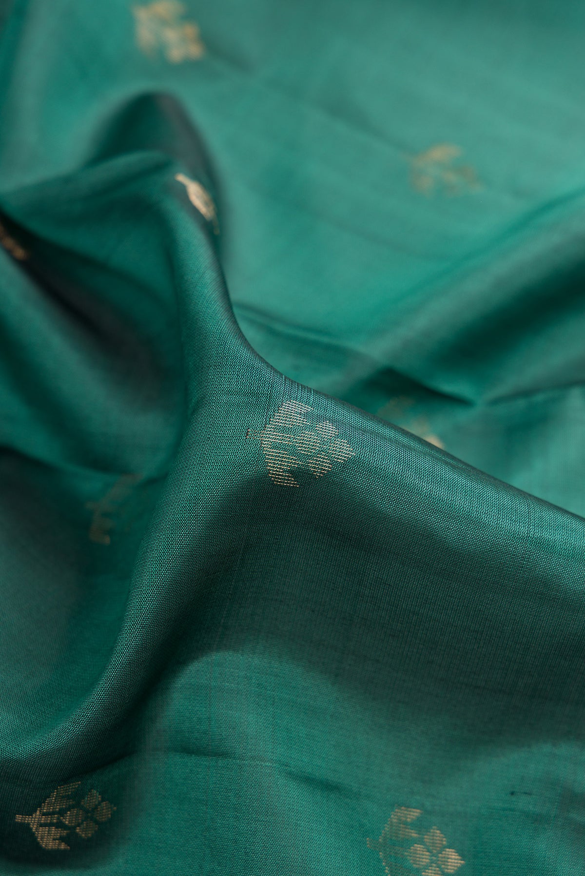 Close up of Pure Silk Green Soft Saree with Zari Butta on the body and Zari Border.  displaying folds