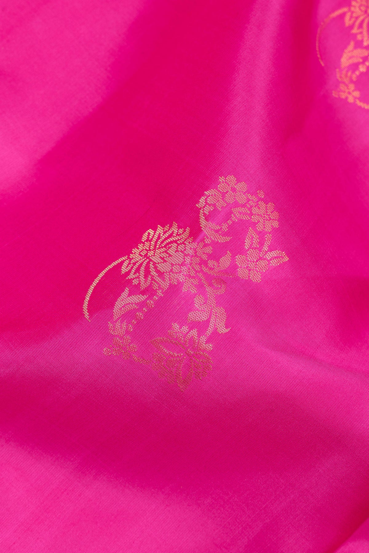 Close up of Pure Silk Rani Pink Soft Saree with Zari Butta on the body and Zari Border.  displaying folds