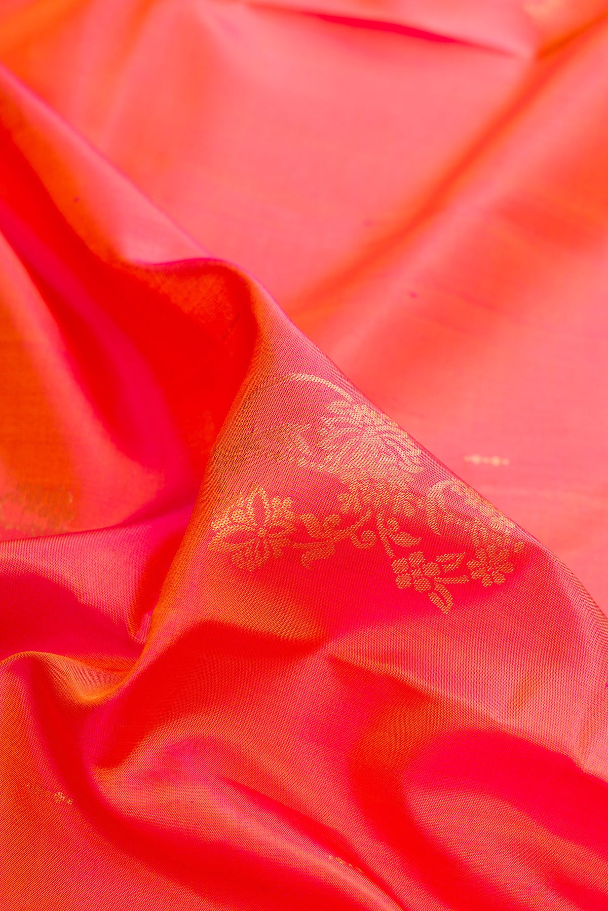 Close up of Pure Silk Coral Dual Tone Soft Saree with Zari Butta on the body and Zari Border.  displaying folds