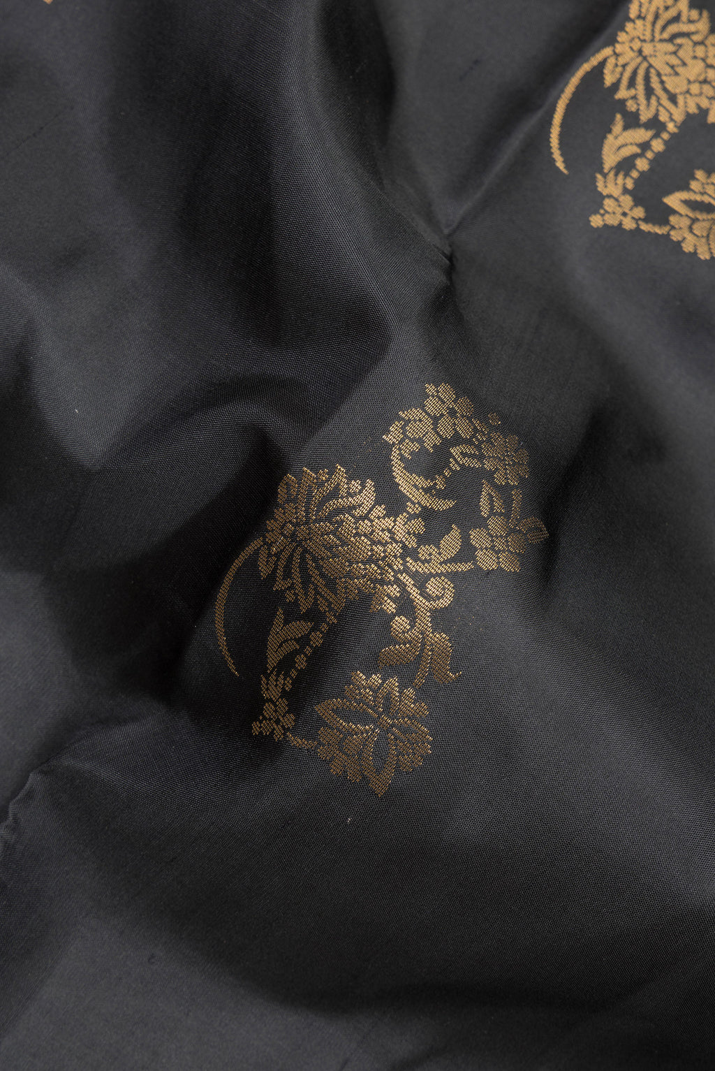 Close up of Pure Silk Black Soft Saree with Zari Butta on the body and Zari Border.  displaying folds
