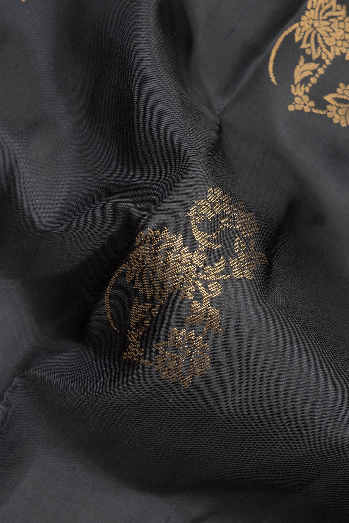 Close up of Pure Silk Black Soft Saree with Zari Butta on the body and Zari Border.  displaying folds