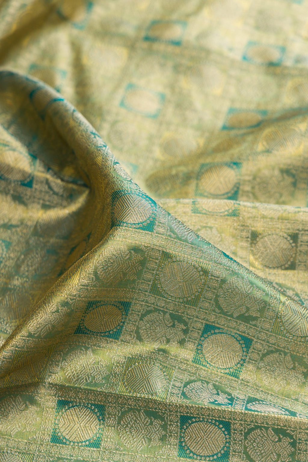 Close up of Green Dual Tone Kanchipuram Tissue Saree with Zari Brocade on the body and Zari Border.  displaying folds