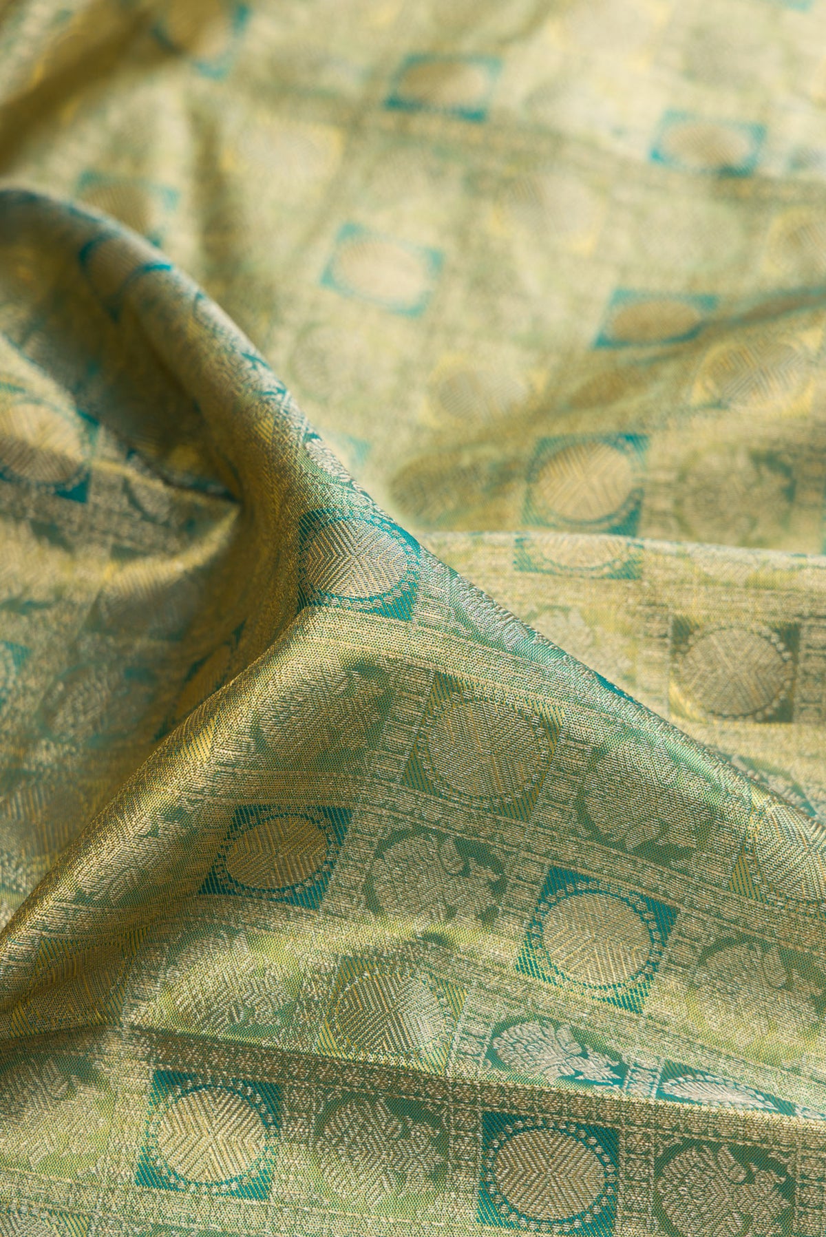 Close up of Green Dual Tone Kanchipuram Tissue Saree with Zari Brocade on the body and Zari Border.  displaying folds