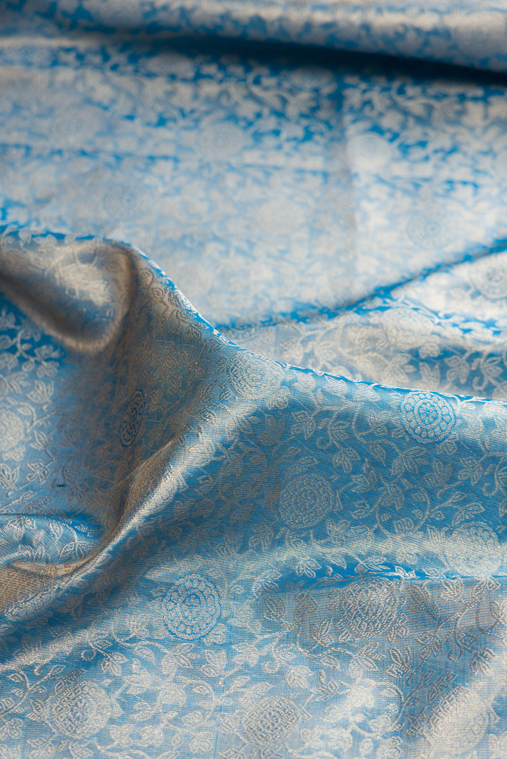 Close up of Peacock Blue Dual Tone Kanjivaram Tissue Saree with Zari Brocade on the body and Zari Border.  displaying folds