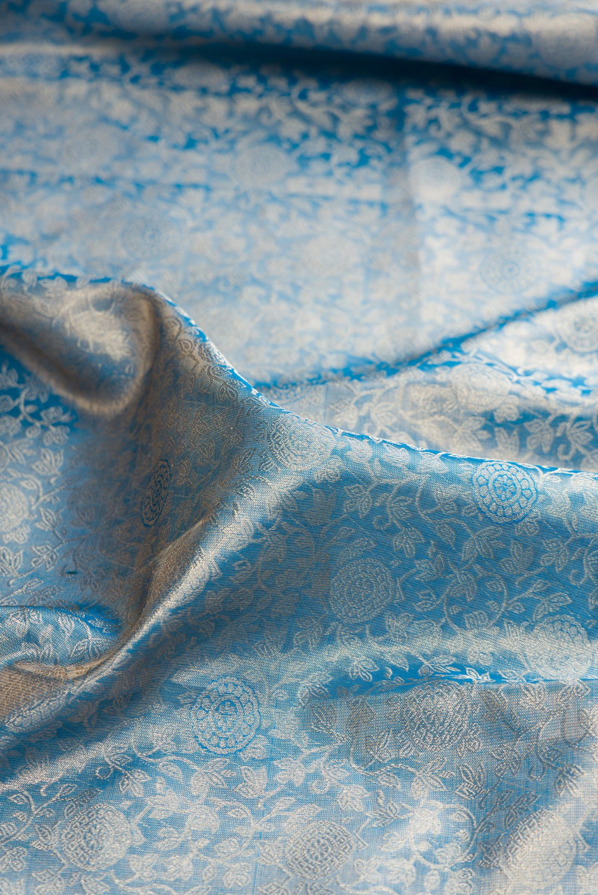 Close up of Peacock Blue Dual Tone Kanjivaram Tissue Saree with Zari Brocade on the body and Zari Border.  displaying folds