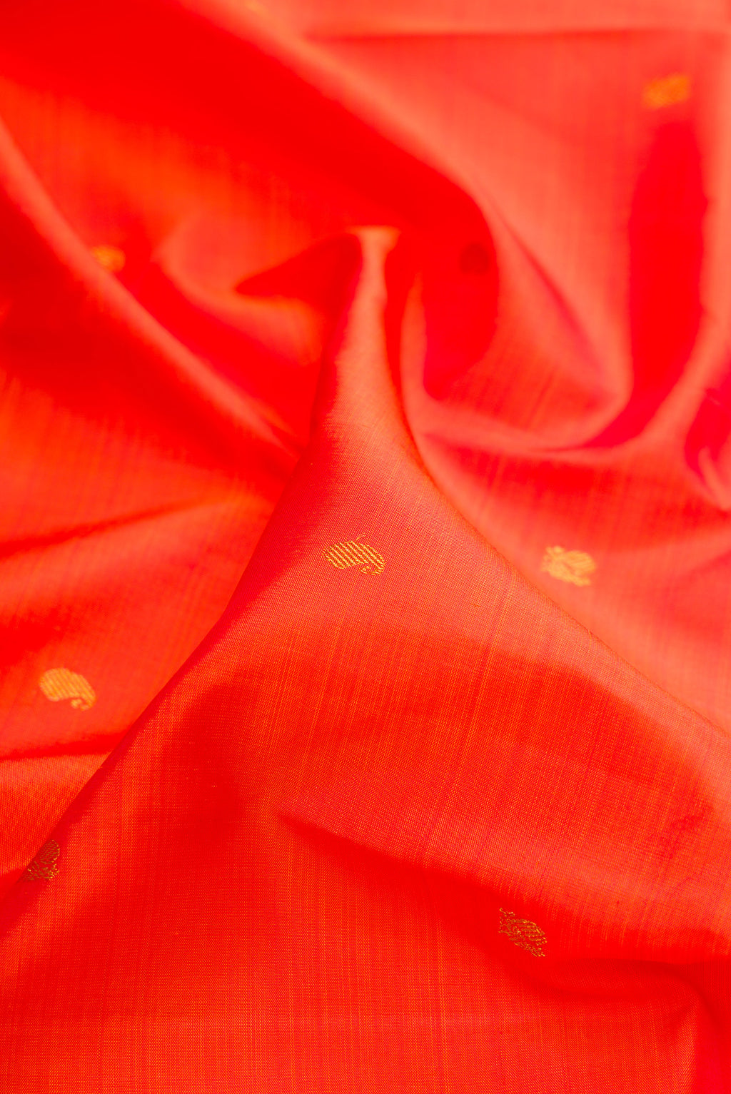 Close up of Pure Silk Orange Kanchipuram Saree with Zari Butta on the body and Zari Border.  displaying folds