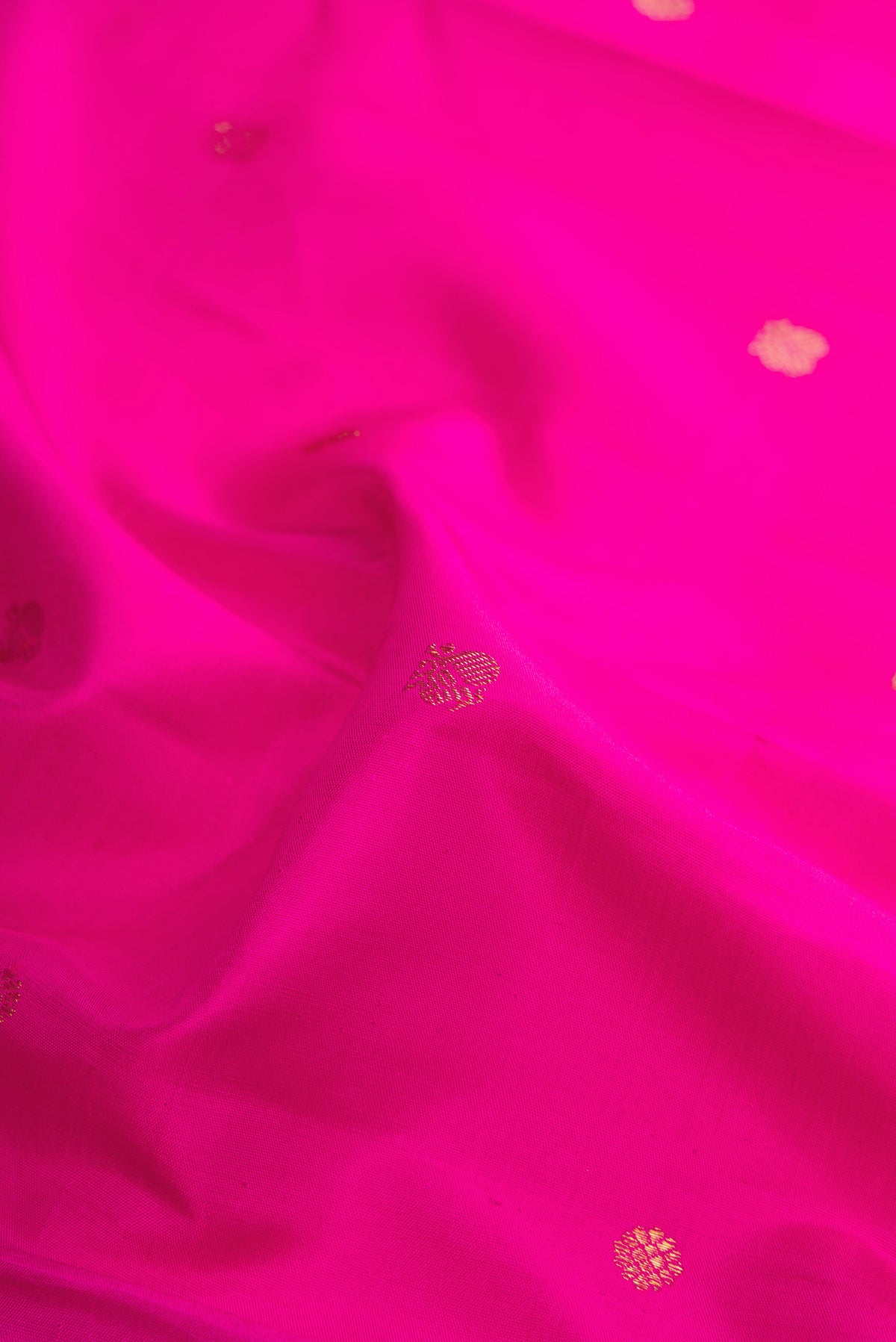 Close up of Pure Silk Rani Pink Kanchipuram Saree with Zari Butta on the body and Zari Border.  displaying folds