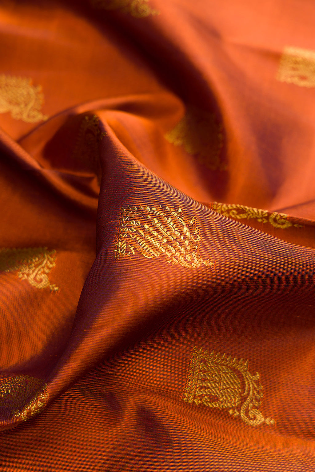 Close up of Pure Silk Rust Kanchipuram Saree with Zari Butta on the body and Fancy Border.  displaying folds