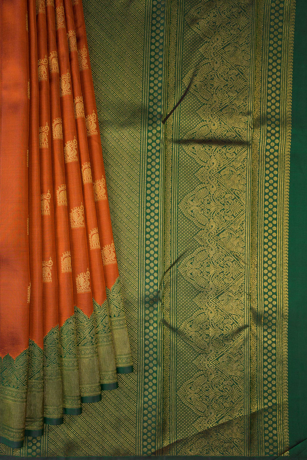 Pleats and pallu of Pure Silk Rust Kanchipuram Saree with Zari Butta on the body and Fancy Border. 