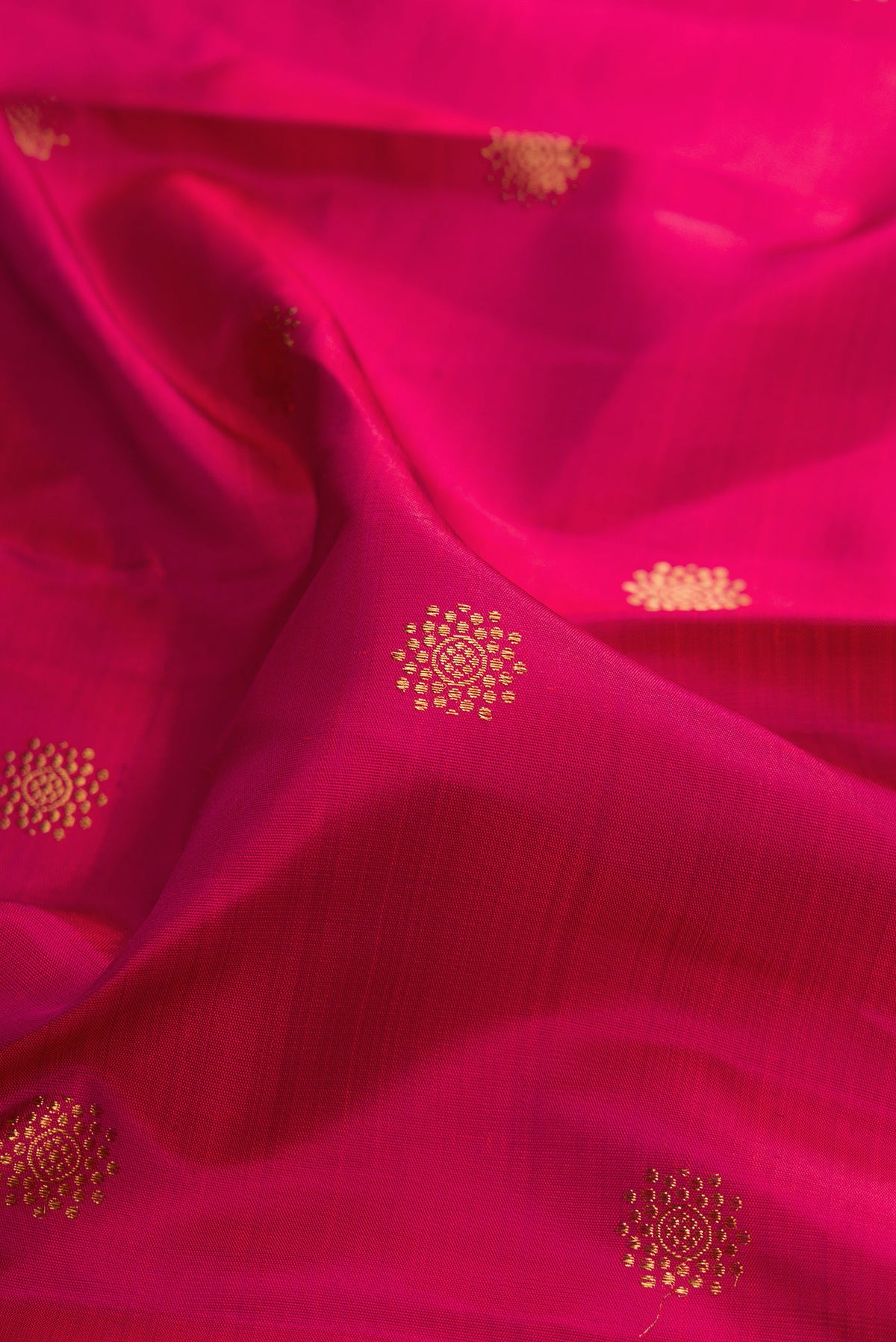Close up of Pure Silk Dark Pink Kanchipuram Saree with Zari Butta on the body and Zari Border.  displaying folds