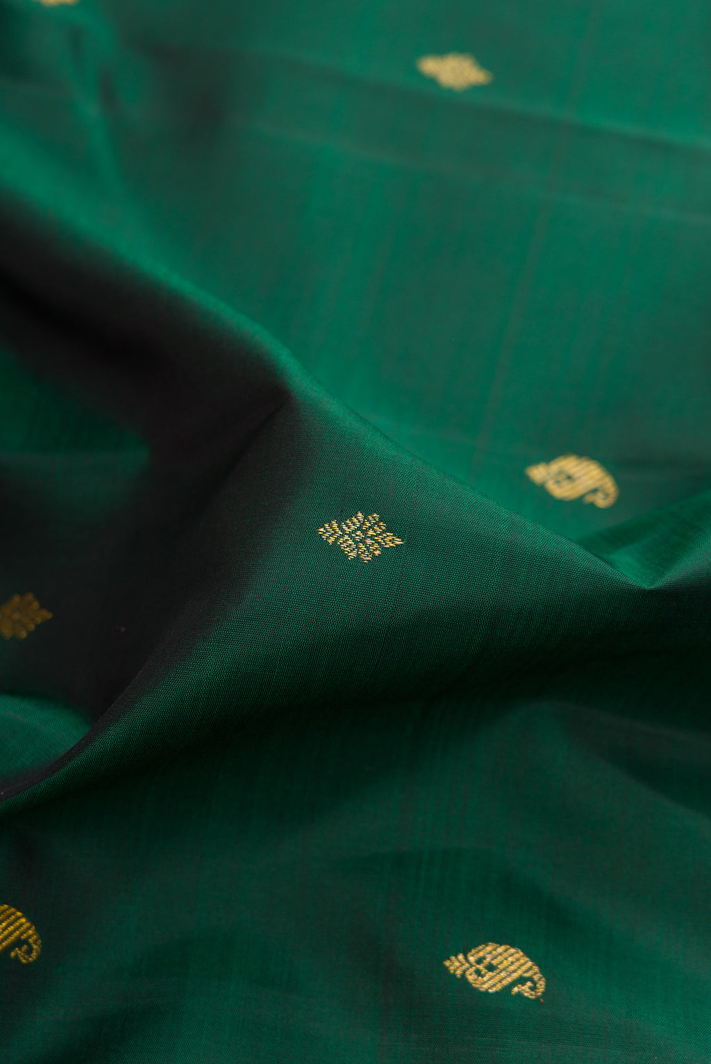 Close up of Pure Silk Bottle Green Kanchipuram Saree with Zari Butta on the body and Zari Border.  displaying folds