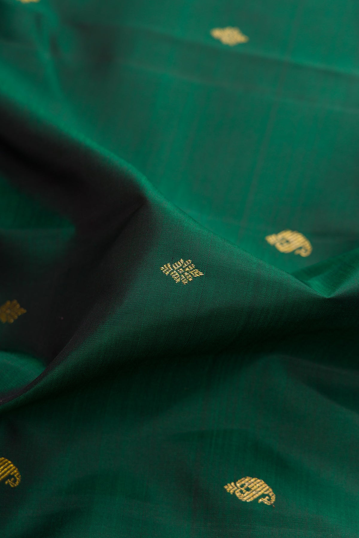 Close up of Pure Silk Bottle Green Kanchipuram Saree with Zari Butta on the body and Zari Border.  displaying folds