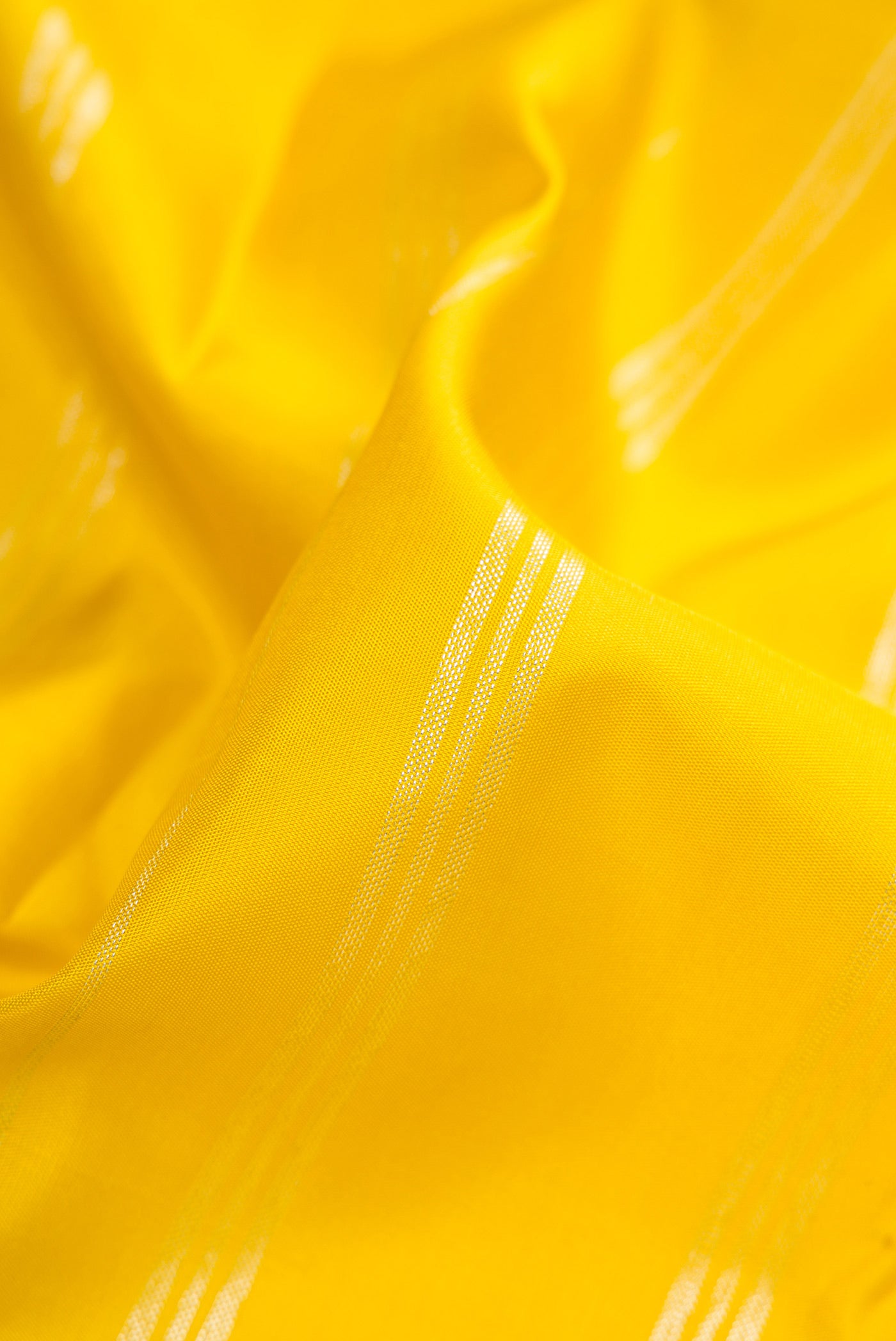 Close up of Yellow Kanjivaram Silk Saree with Stripes on the body and Without Border.  displaying folds