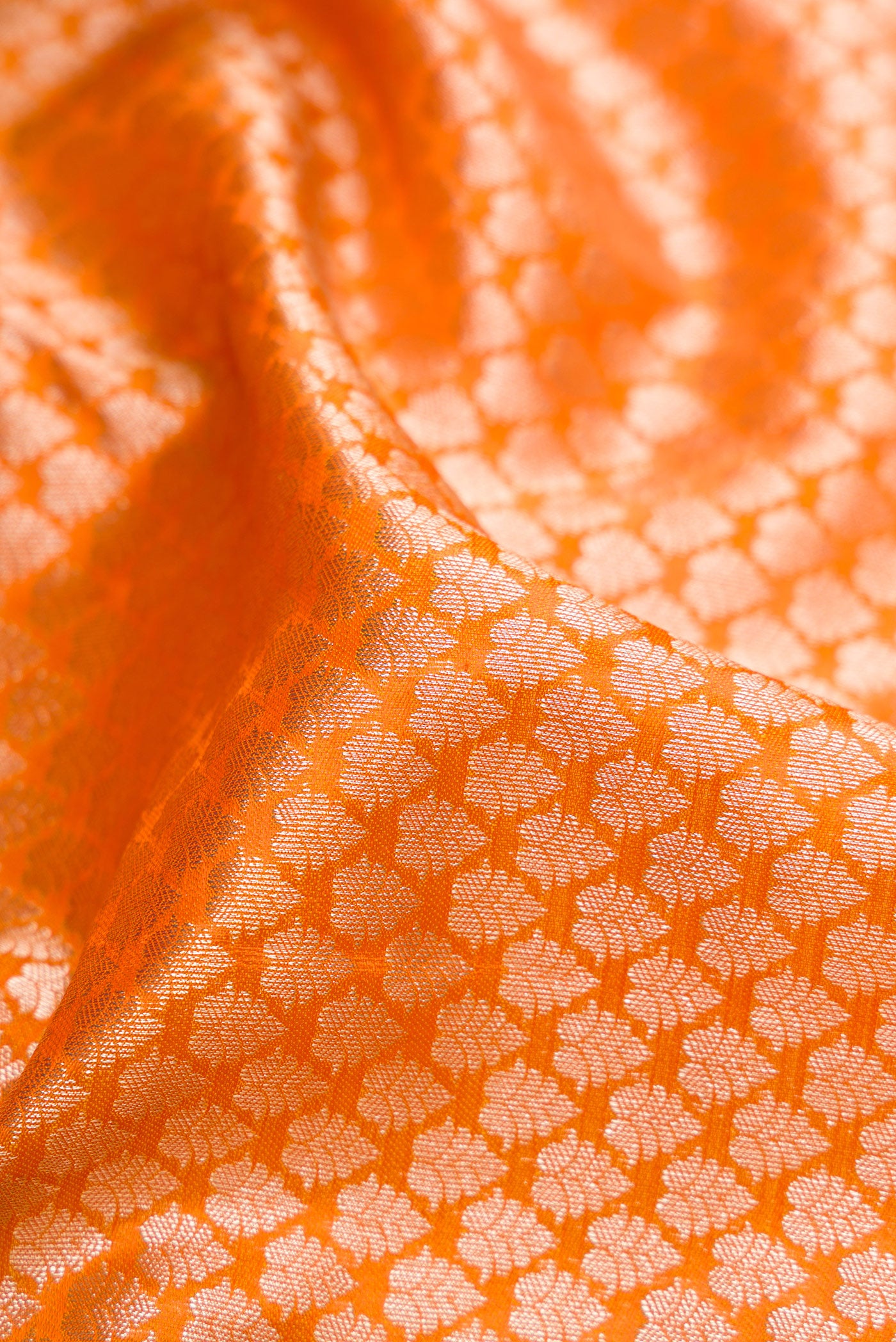 Close up of Orange Kanchipuram Tissue Silk Saree with Zari Brocade on the body and Fancy Border.  displaying folds