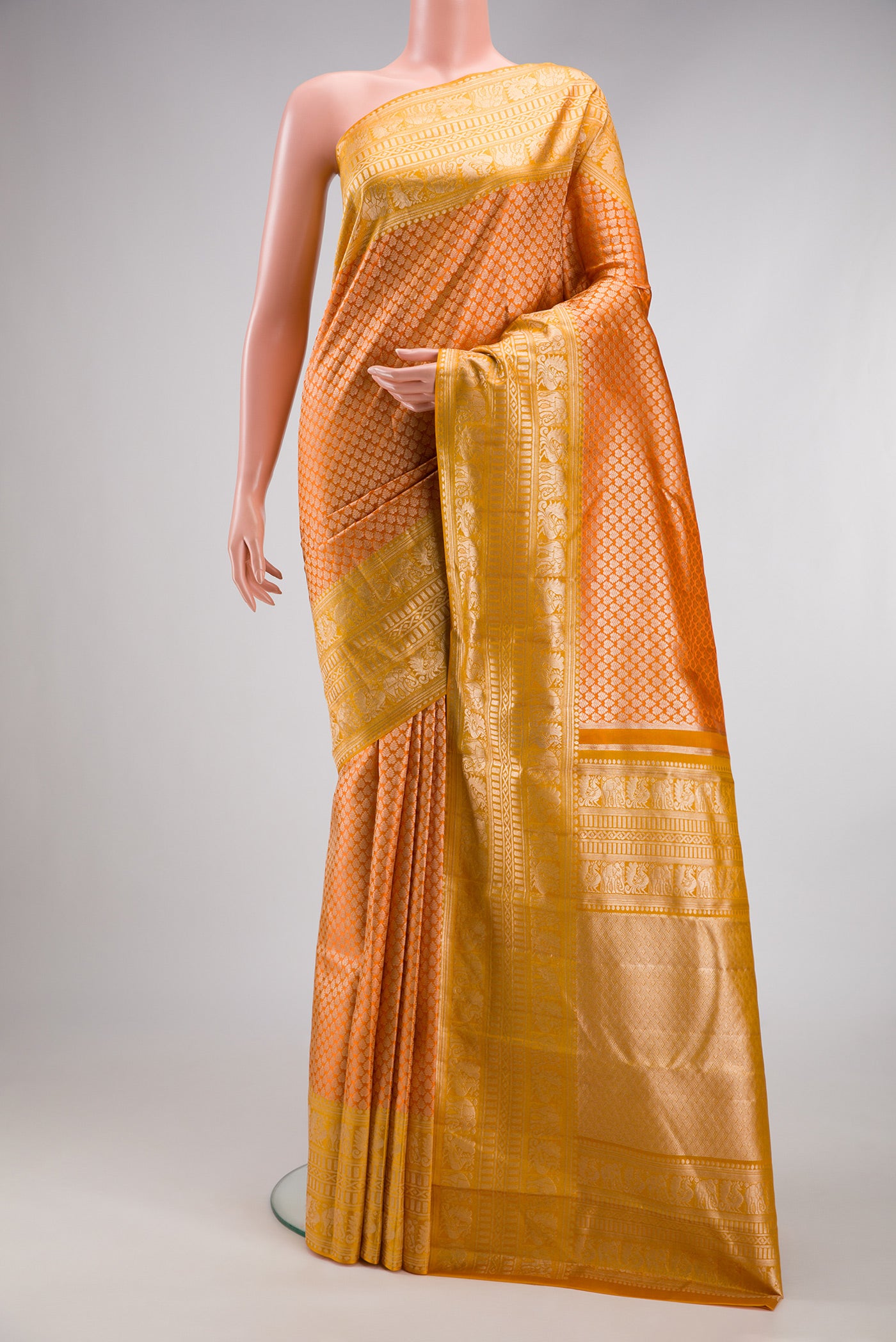 Orange Kanchipuram Tissue Silk Saree with Zari Brocade on the body and Fancy Border.  displayed on a mannequin