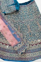 Flat lay of Peacock Blue Banarasi Silk Womens Lehenga set featuring Embroidered Choli paired with Peacock Blue Embroidered Skirt with Embroidered Border and a Embroidered dupatta in Pink