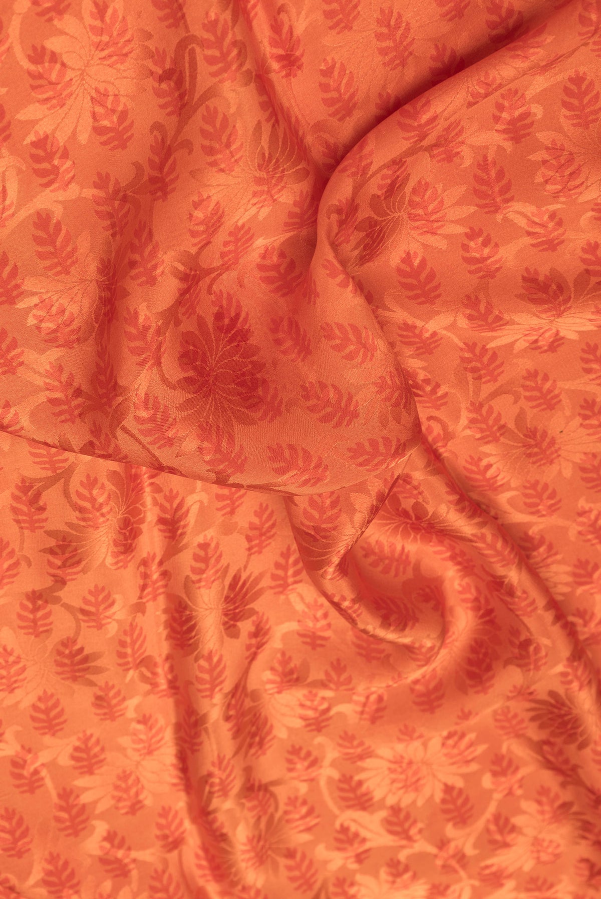 Close up of Orange Dual Tone Mysore Crepe Saree with Printed design on the body and Printed Border.  displaying folds