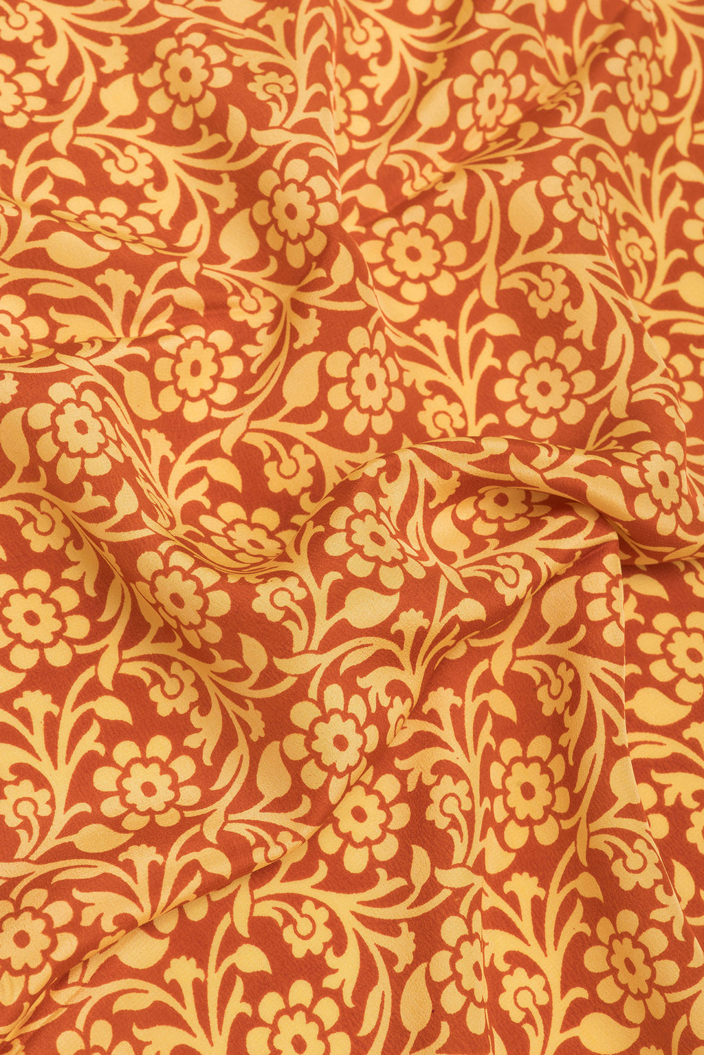 Close up of Rust Crepe Saree with Printed design on the body and Plain Border.  displaying folds