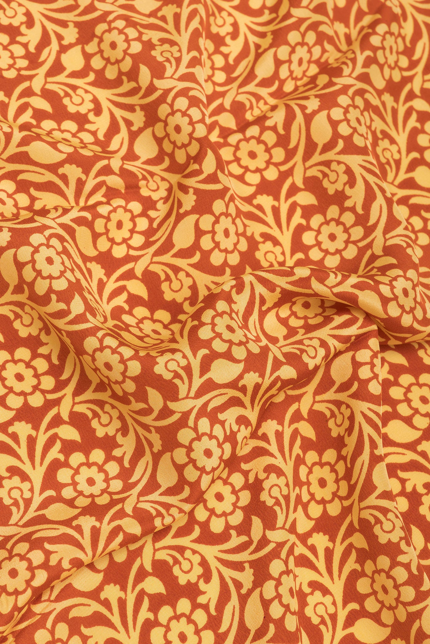 Close up of Rust Crepe Saree with Printed design on the body and Plain Border.  displaying folds