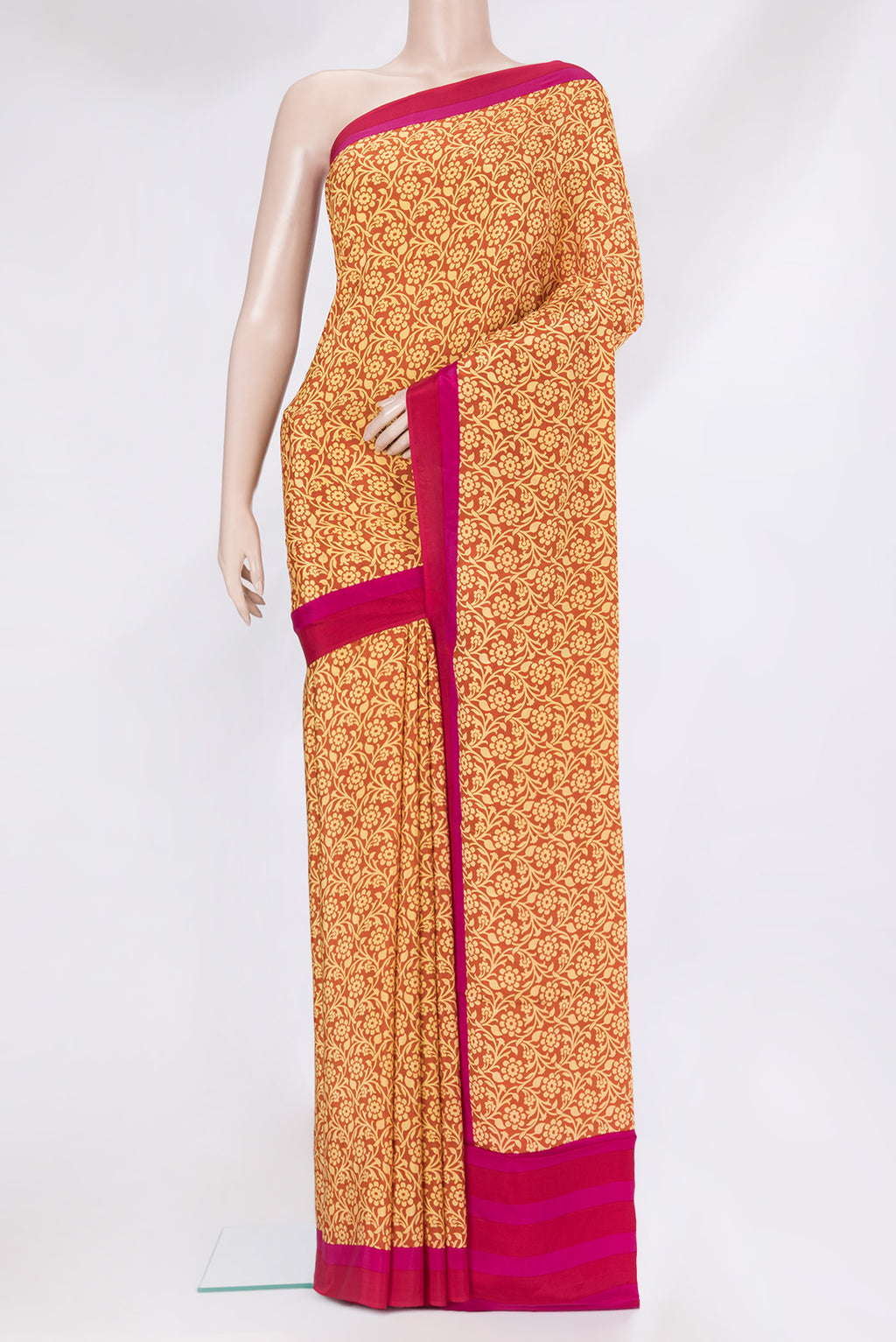 Rust Crepe Saree with Printed design on the body and Plain Border.  displayed on a mannequin
