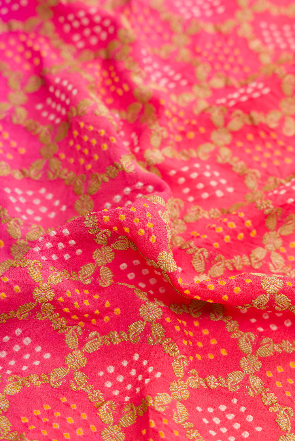 Close up of Pink and Red Color Banarasi Georgette Saree with Bandhani Print on the body and Zari Border.  displaying folds