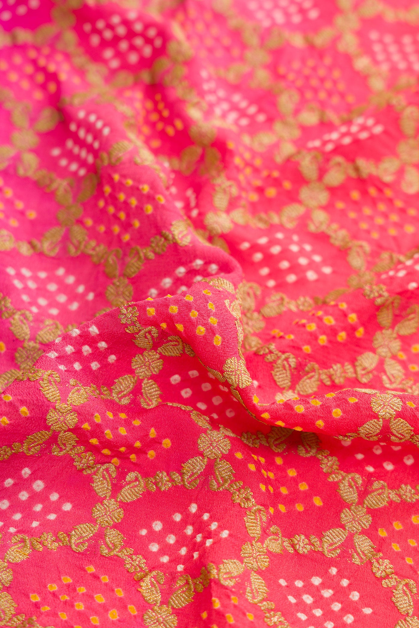 Close up of Pink and Red Color Banarasi Georgette Saree with Bandhani Print on the body and Zari Border.  displaying folds
