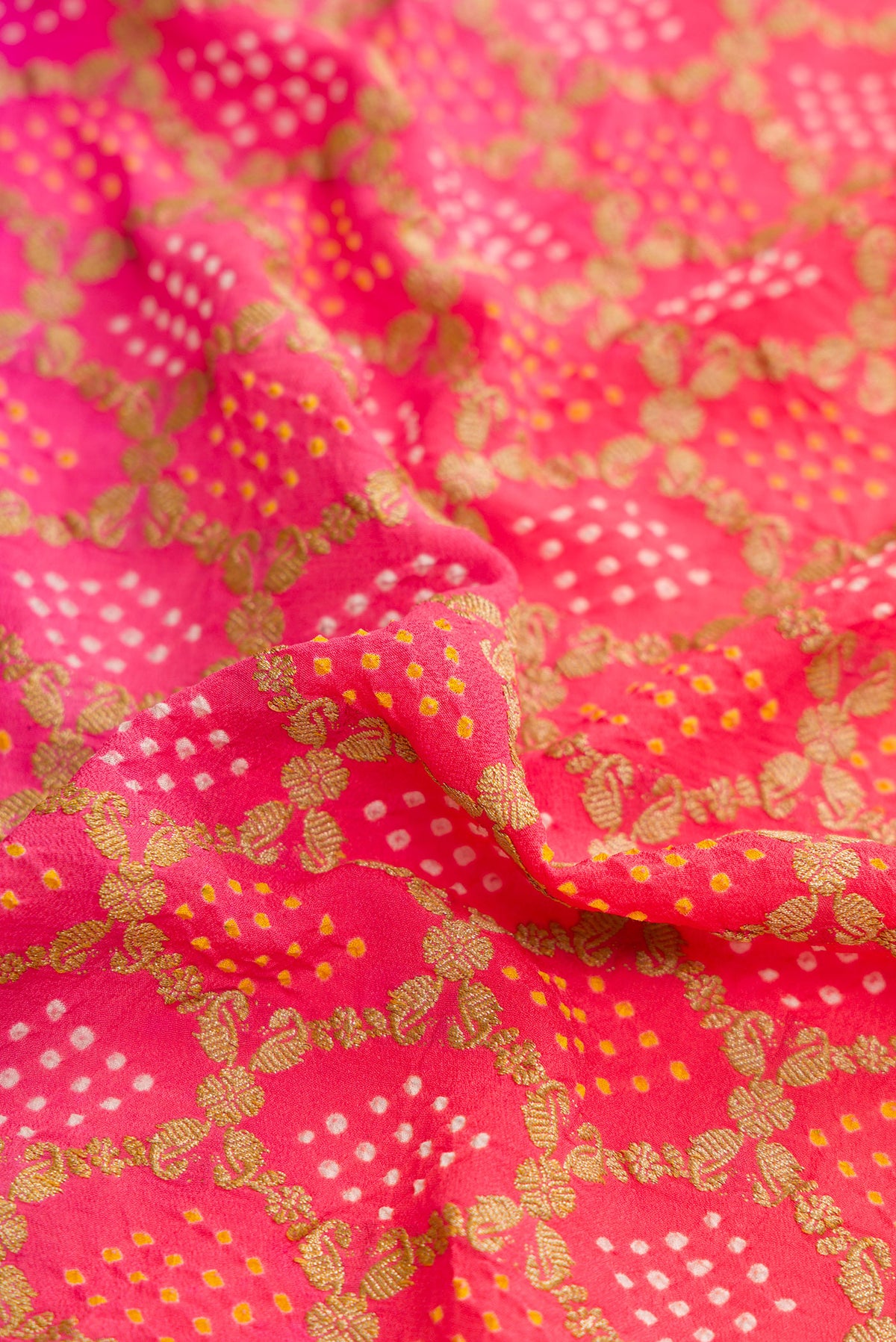 Close up of Pink and Red Color Banarasi Georgette Saree with Bandhani Print on the body and Zari Border.  displaying folds