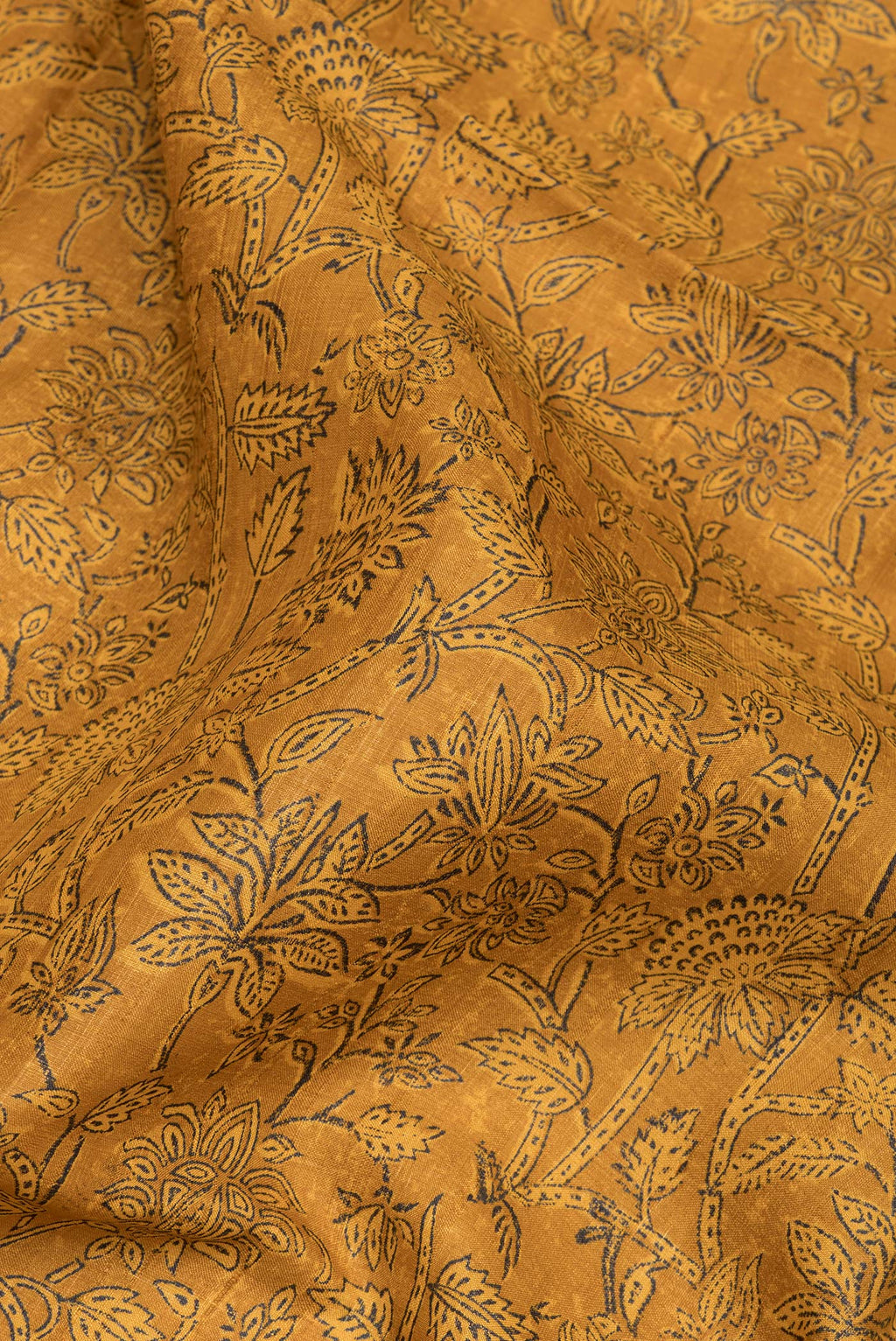 Close up of Mustard Tussar Silk Saree with Printed design on the body and Fancy Border.  displaying folds