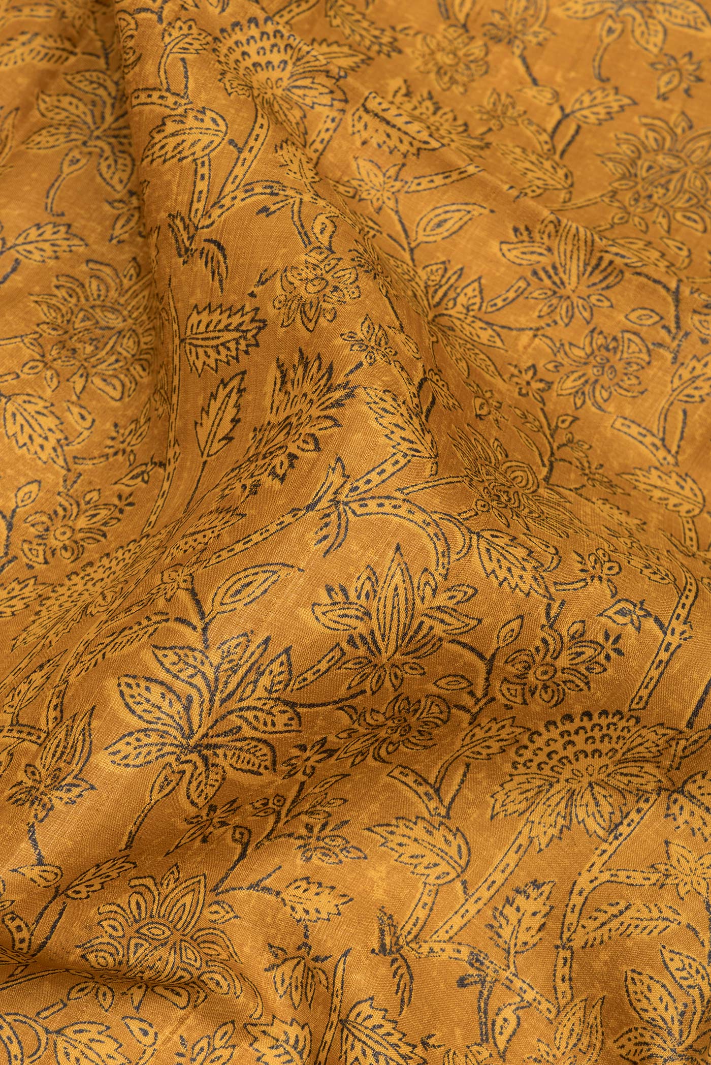 Close up of Mustard Tussar Silk Saree with Printed design on the body and Fancy Border.  displaying folds