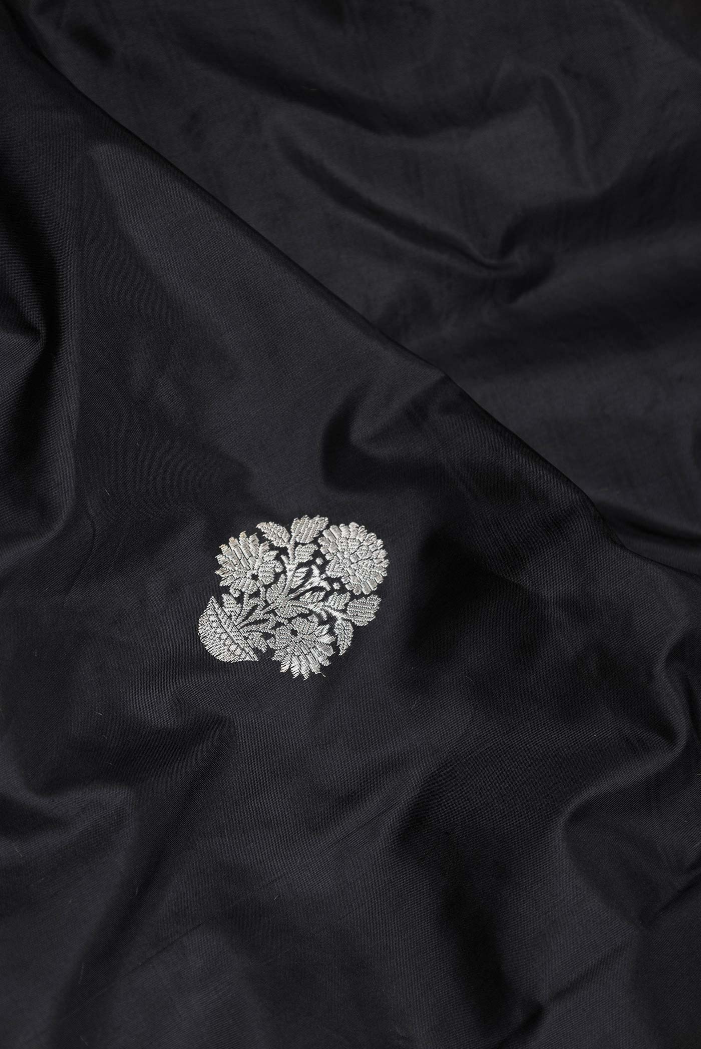 Close up of Black Dual Tone Banarasi Saree with Zari Butta on the body and Without Border displaying folds