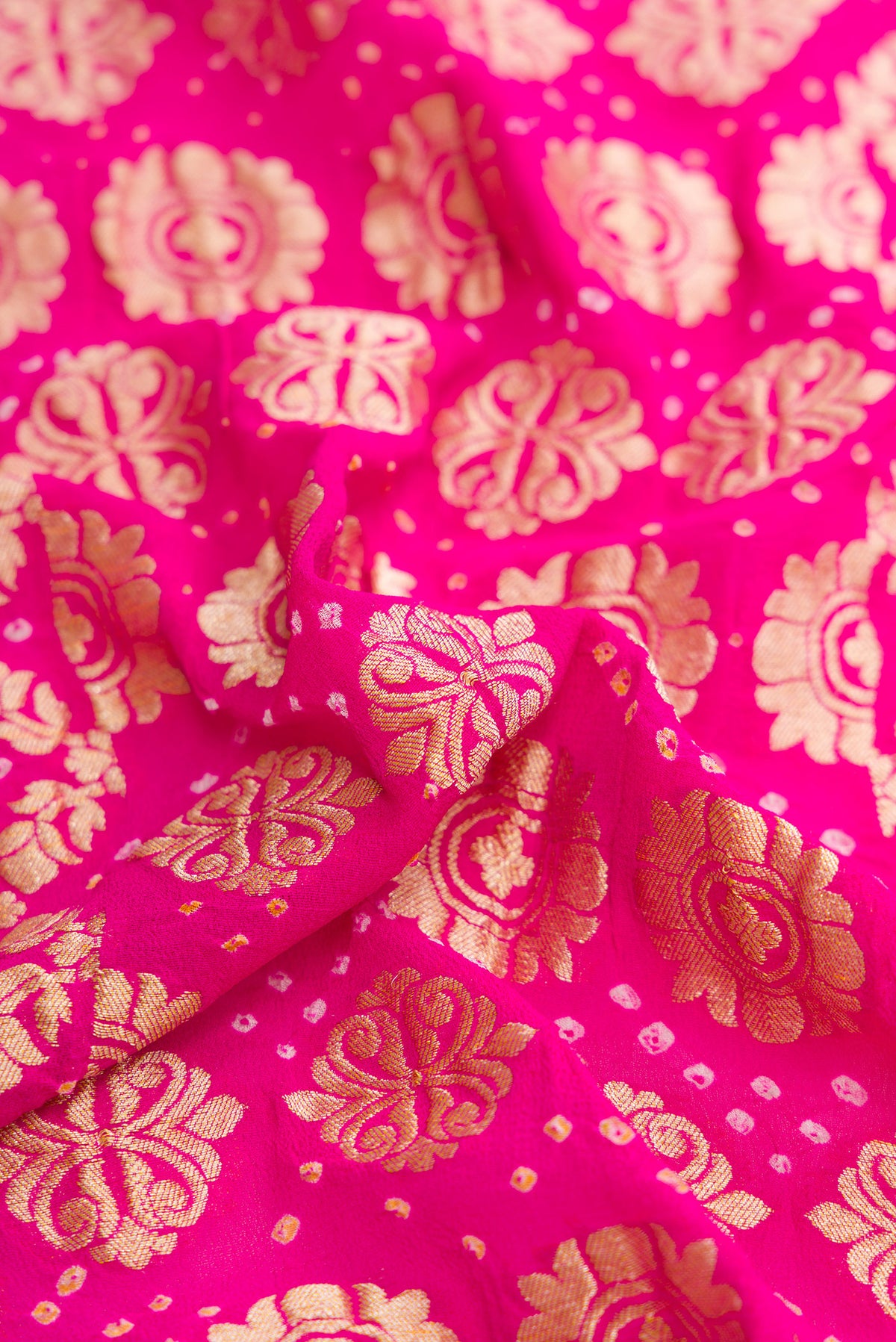 Close up of Pink and Red Color Bandhani Silk Saree with Bandhani Print on the body and Zari Border.  displaying folds