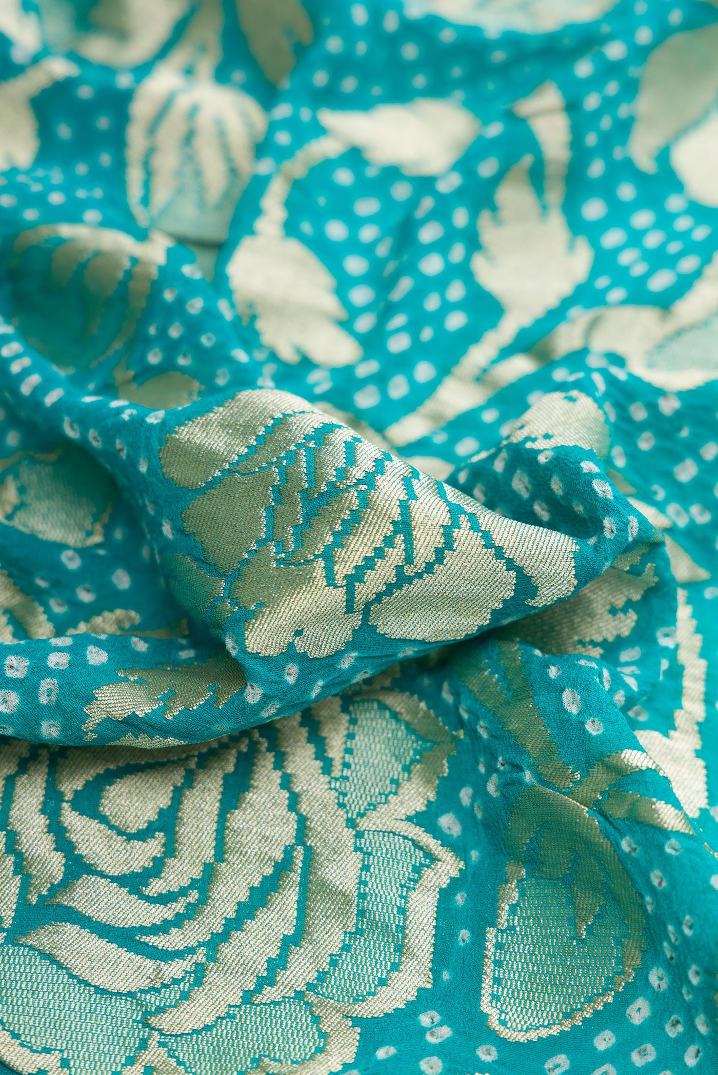 Close up of Sky Blue Dual Tone Bandhani Silk Saree with Bandhani Print on the body and Zari Border.  displaying folds