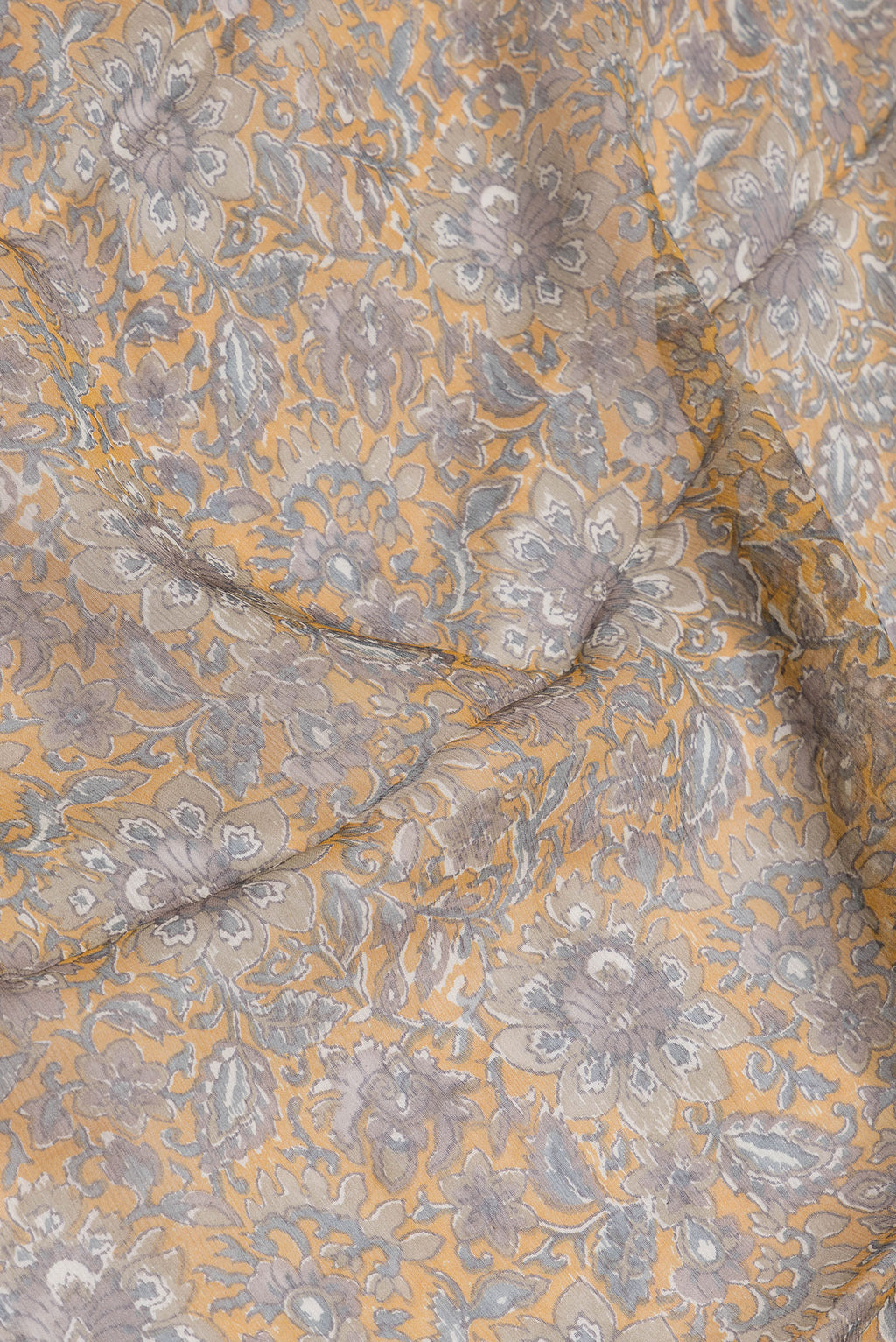 Close up of Mustard Dual Tone Mysore Chiffon Saree with Printed design on the body and Zari And Thread Border.  displaying folds