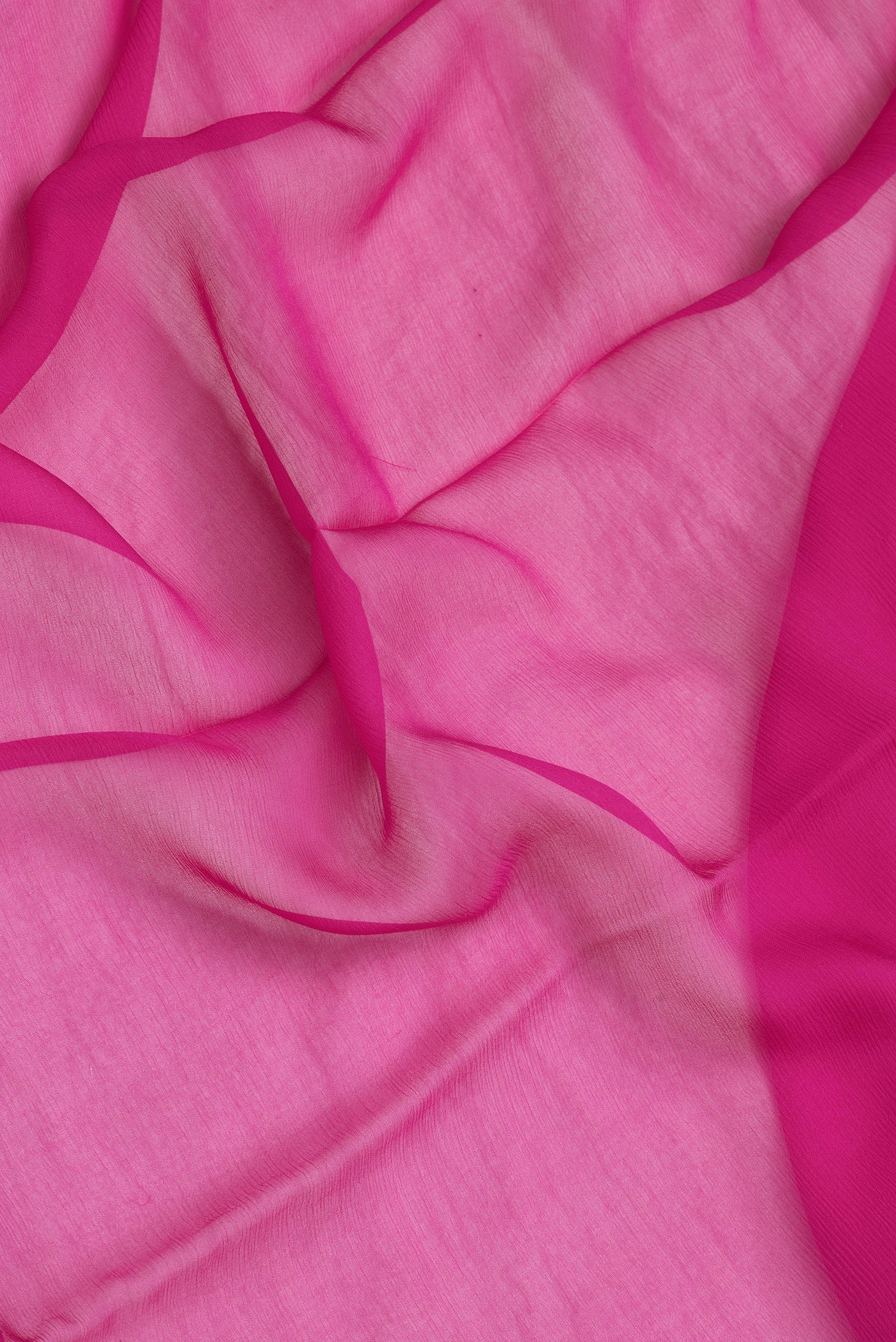 Close up of Pink Dual Tone Georgette Saree with Plain Body and Zari Border.  displaying folds