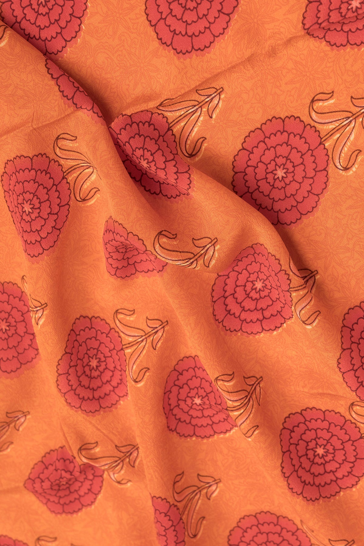 Close up of Orange Dual Tone Mysore Crepe Saree with Printed design on the body and Printed Border.  displaying folds