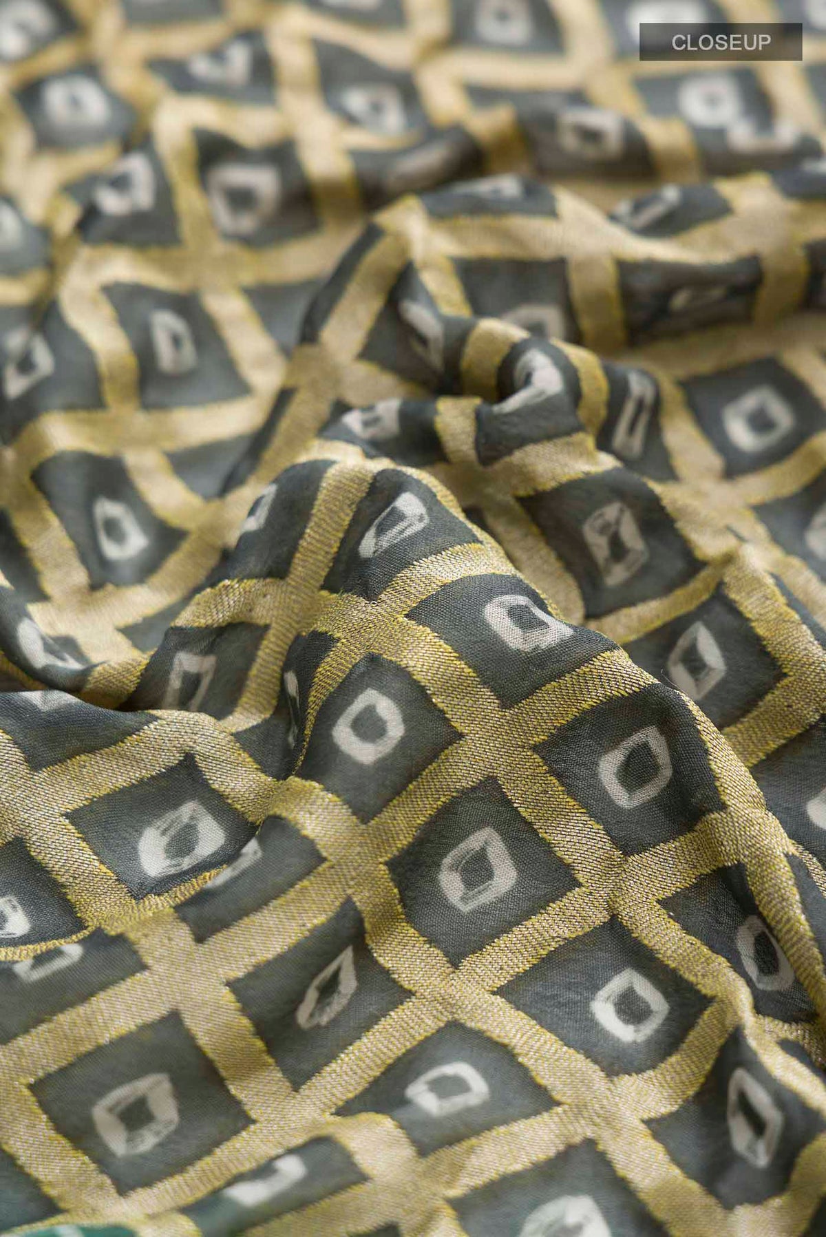 Close up of Grey Banarasi Georgette Saree with Bandhani Print on the body and Zari Border displaying folds