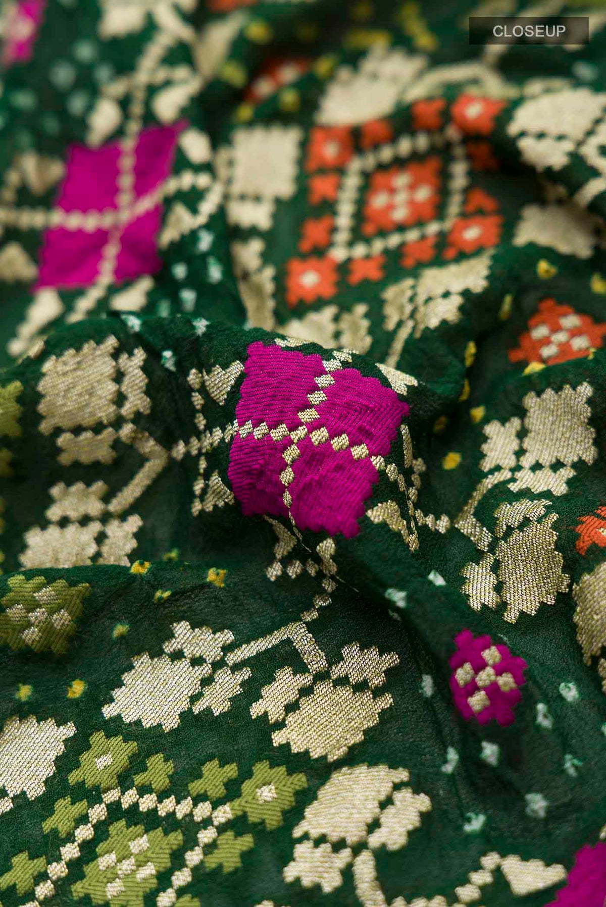 Close up of Green Banarasi Georgette Saree with Bandhani Print on the body and Zari Border displaying folds