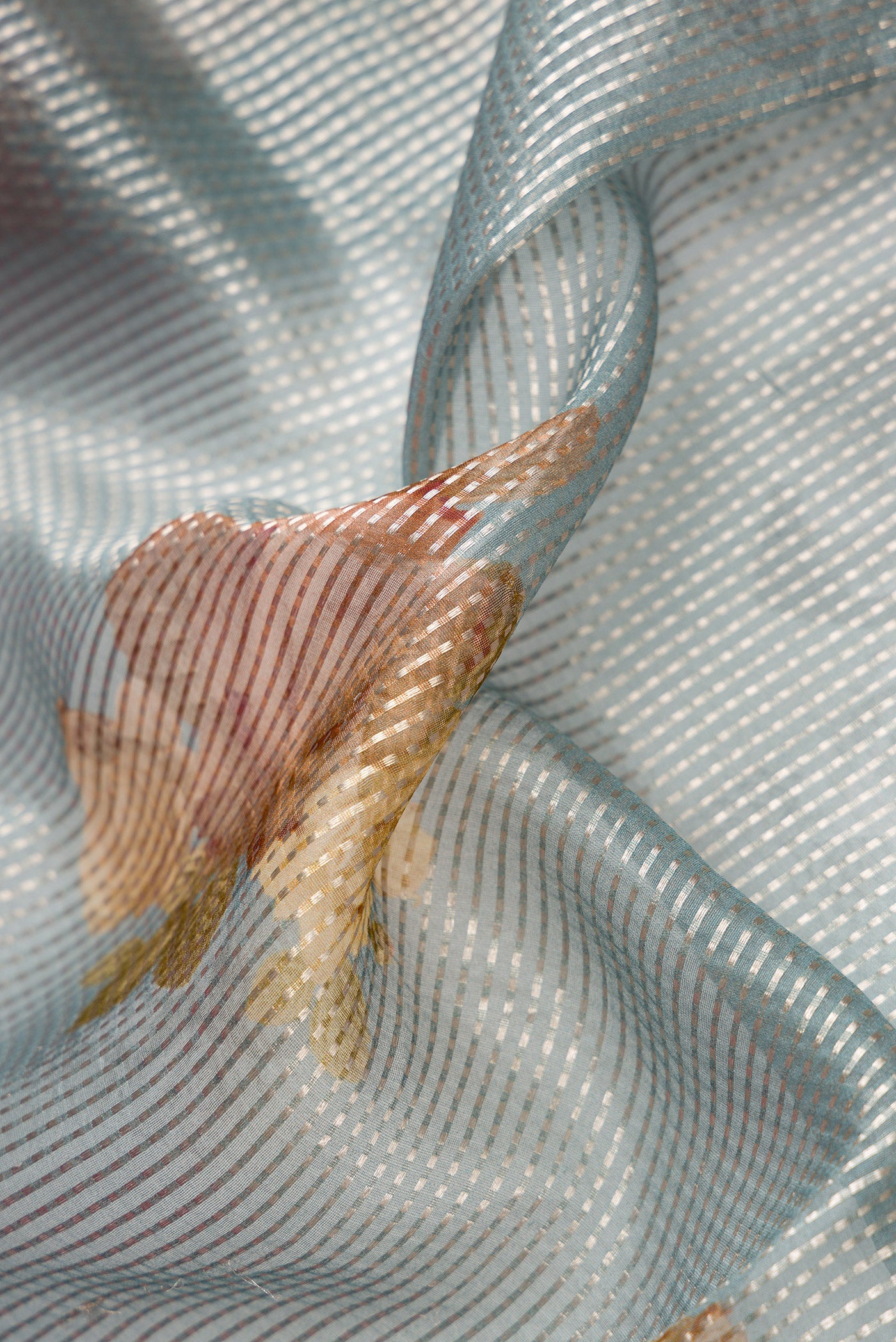 Close up of Grey Dual Tone Organza Silk Saree with Printed design on the body and Without Border.  displaying folds
